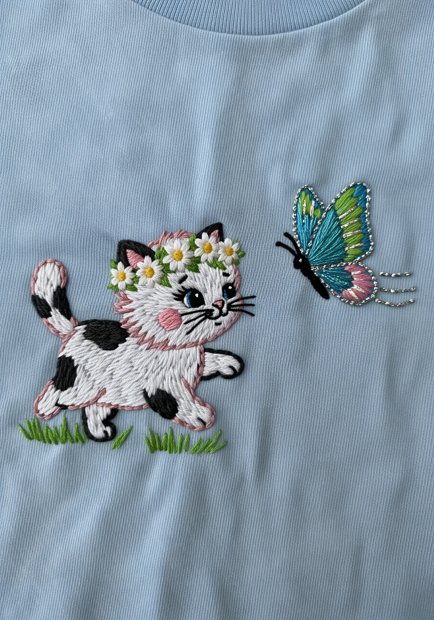 Cartoon kitten with a daisy crown watching a colorful, beaded butterfly.