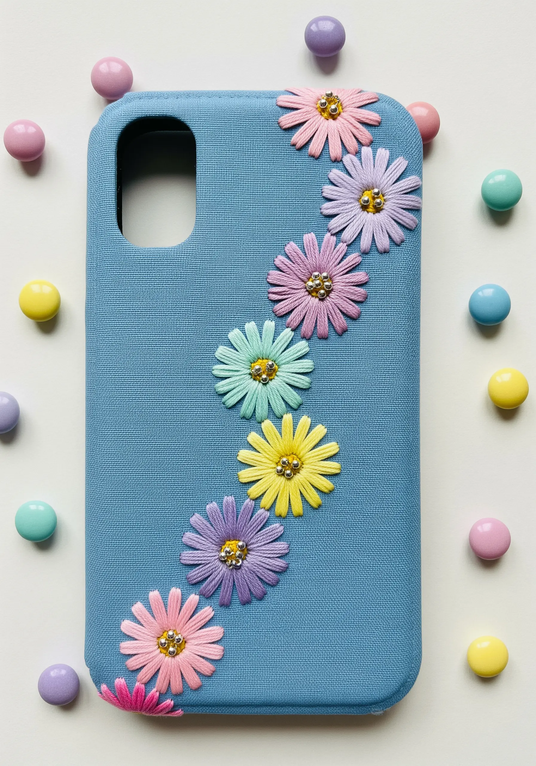 A cascade of pastel rainbow daisies with beaded centers on a blue phone case.