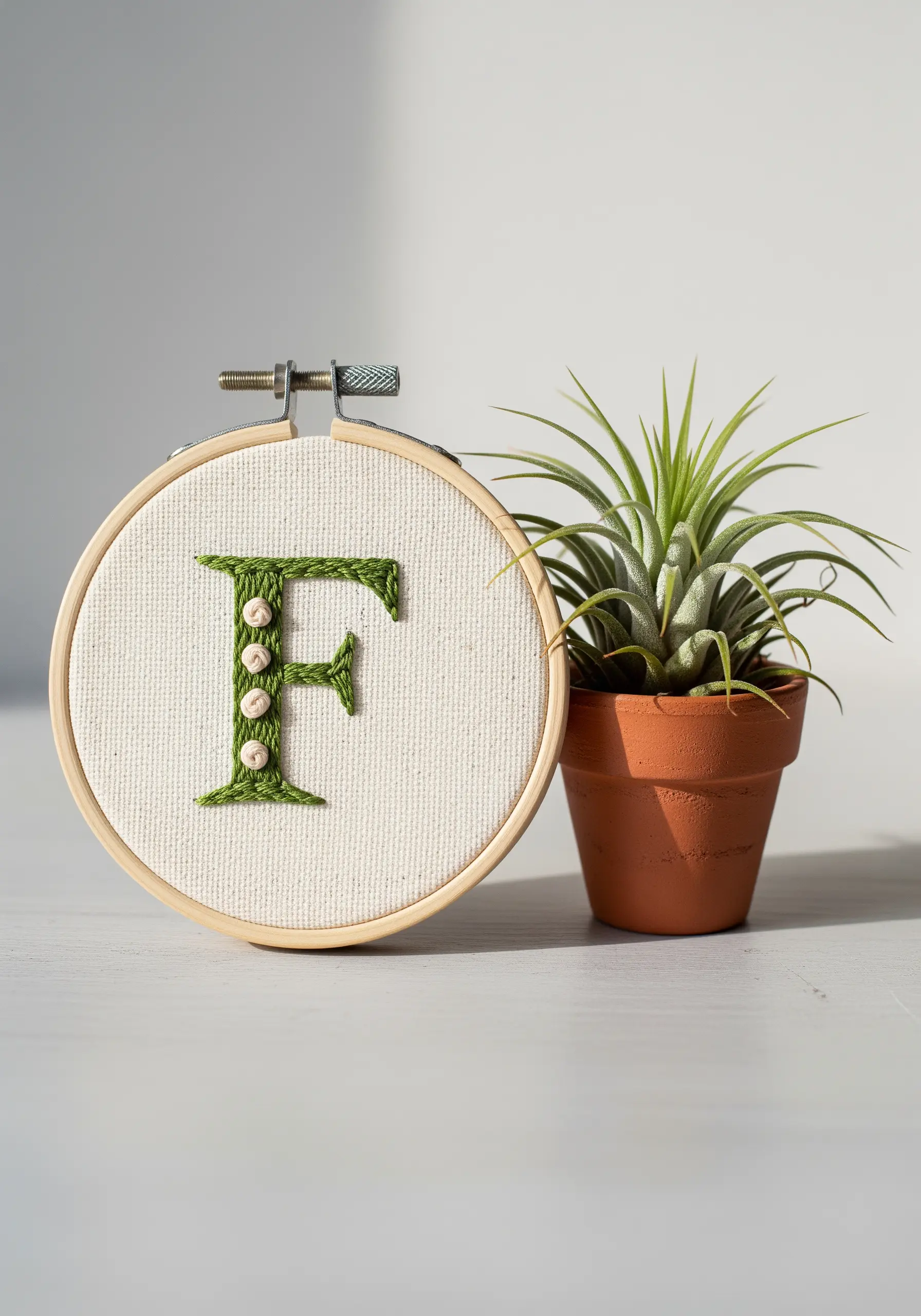 A green embroidered 'F' decorated with small white beads.