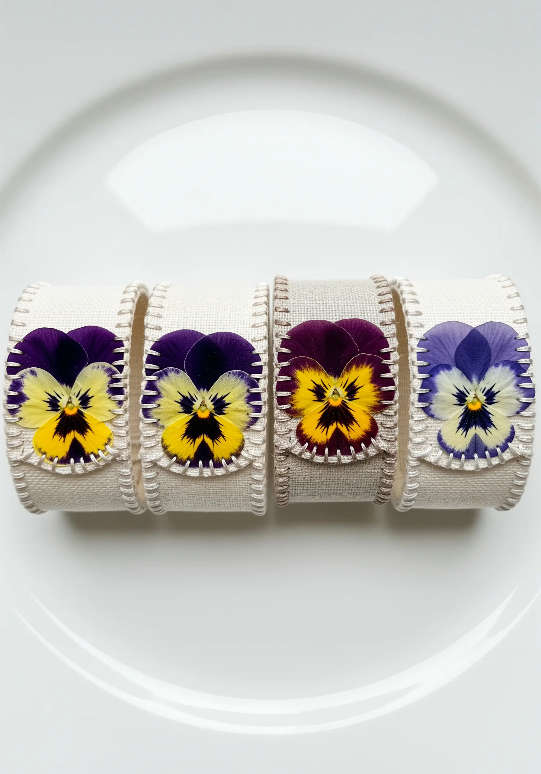 Linen napkin rings, each decorated with a pressed pansy secured by a blanket stitch border.
