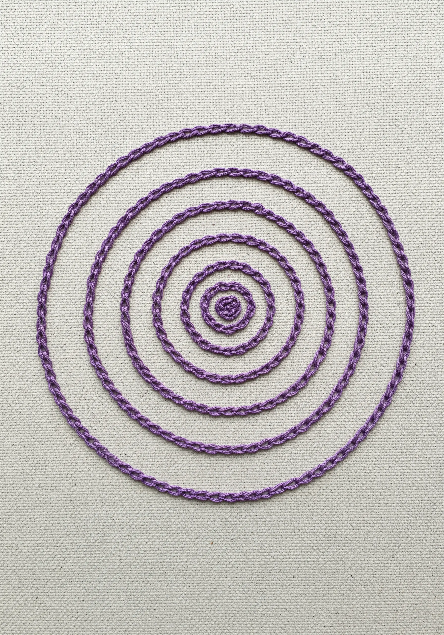 A purple spiral made from a thick, braided-looking chain stitch on canvas.