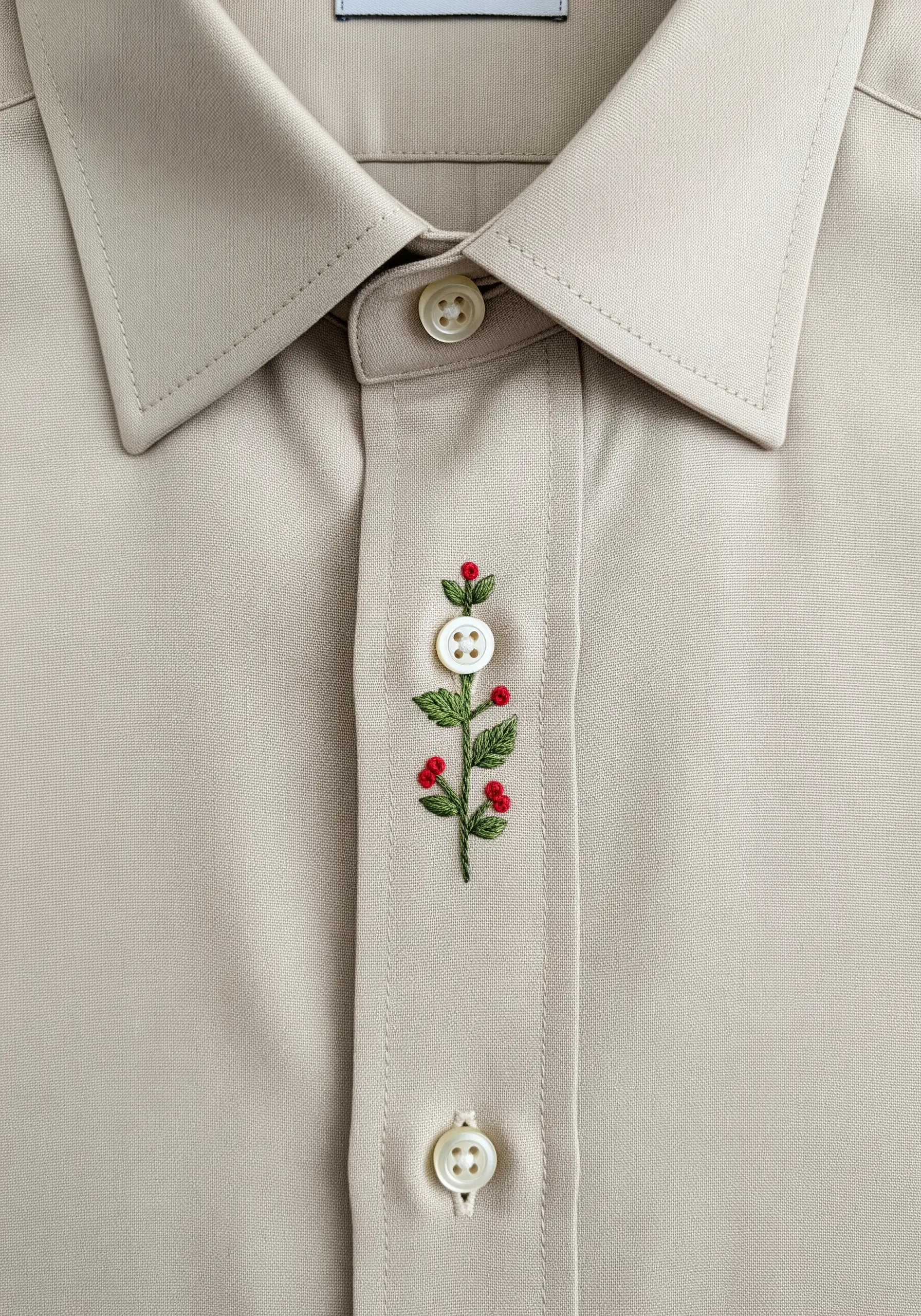 A delicate berry branch embroidered around a button on a shirt placket.
