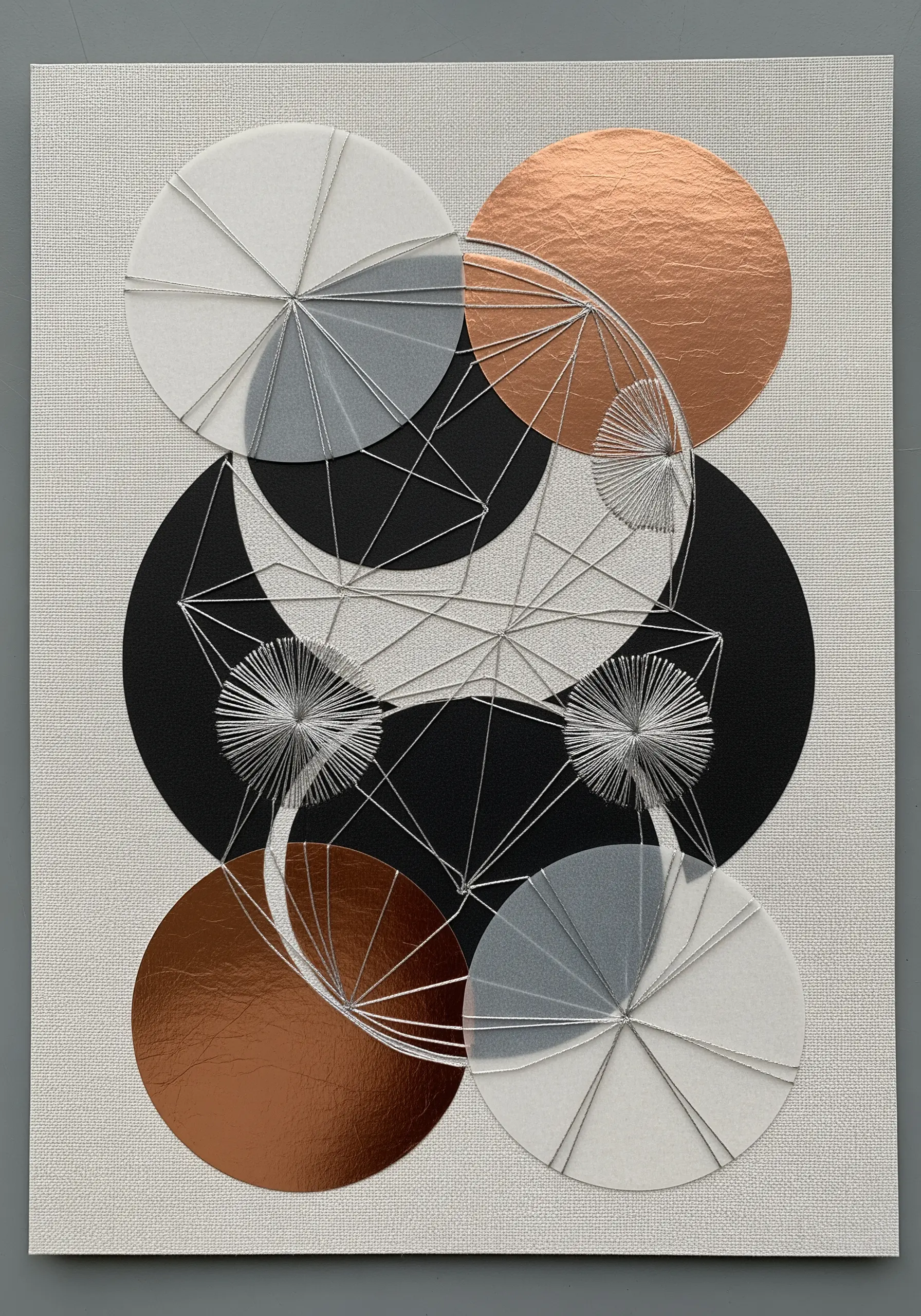 Geometric string art on layered paper circles in copper, black, and white.