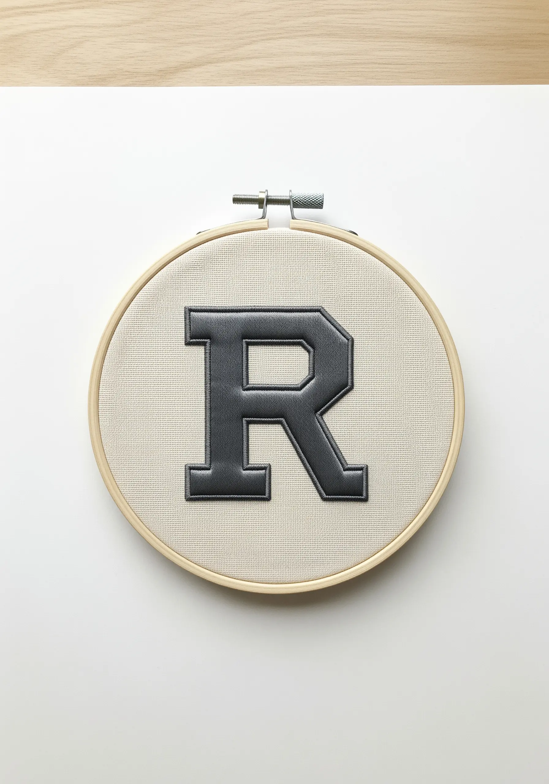 A black faux-leather appliqué letter 'R' with stitched border.