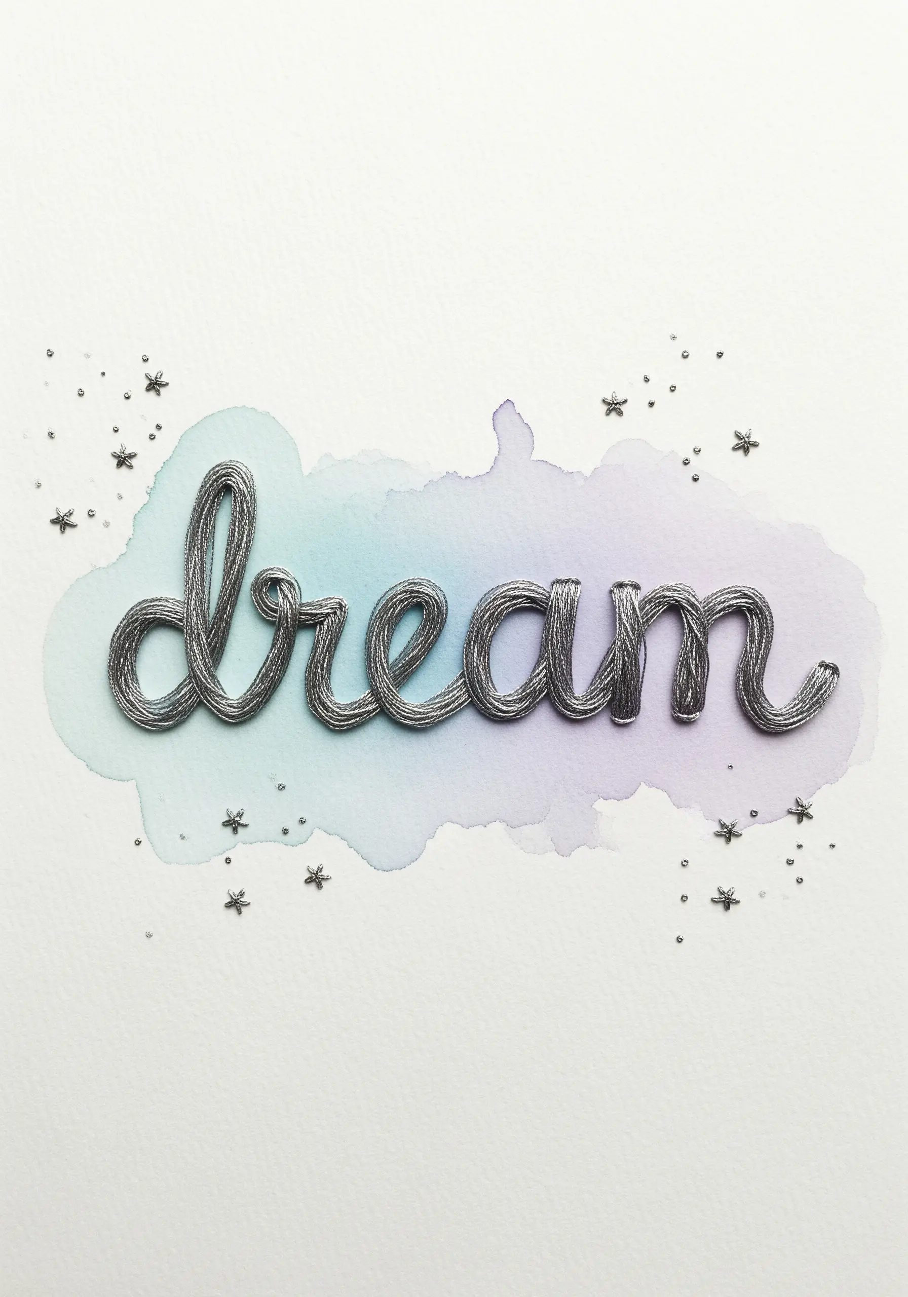The word “dream” in silver cord couched over a soft blue and purple watercolor wash.