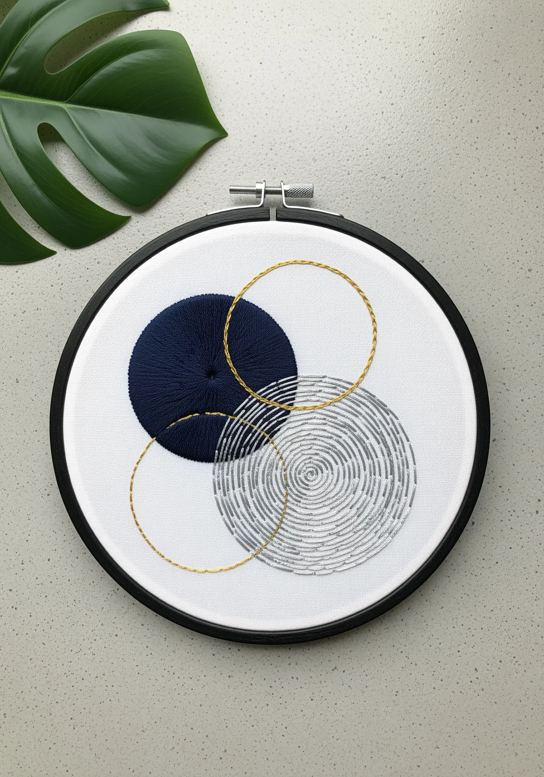 Abstract hoop art with a satin stitched circle, a textured circle, and couched gold rings.
