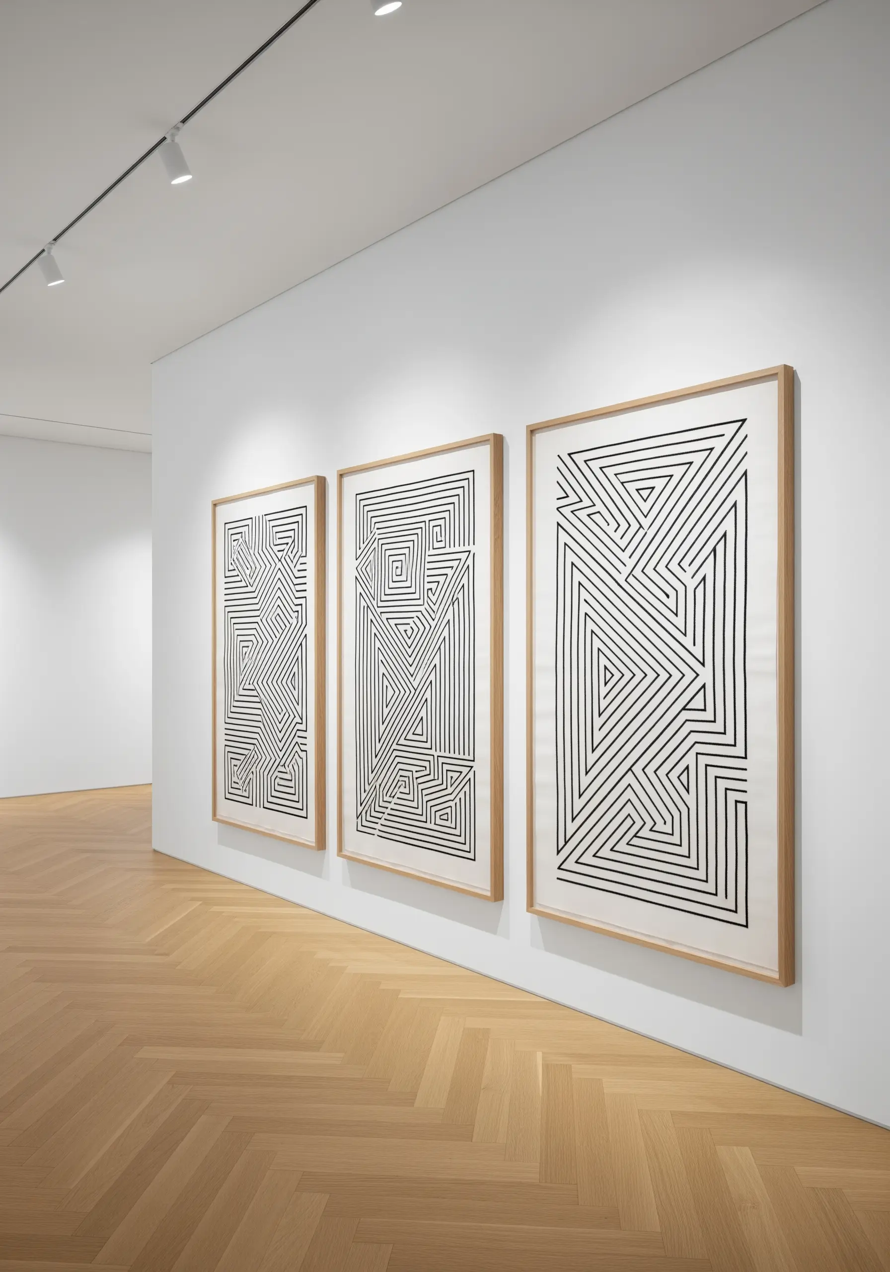 Three large framed geometric black line embroidery pieces hanging in a gallery setting