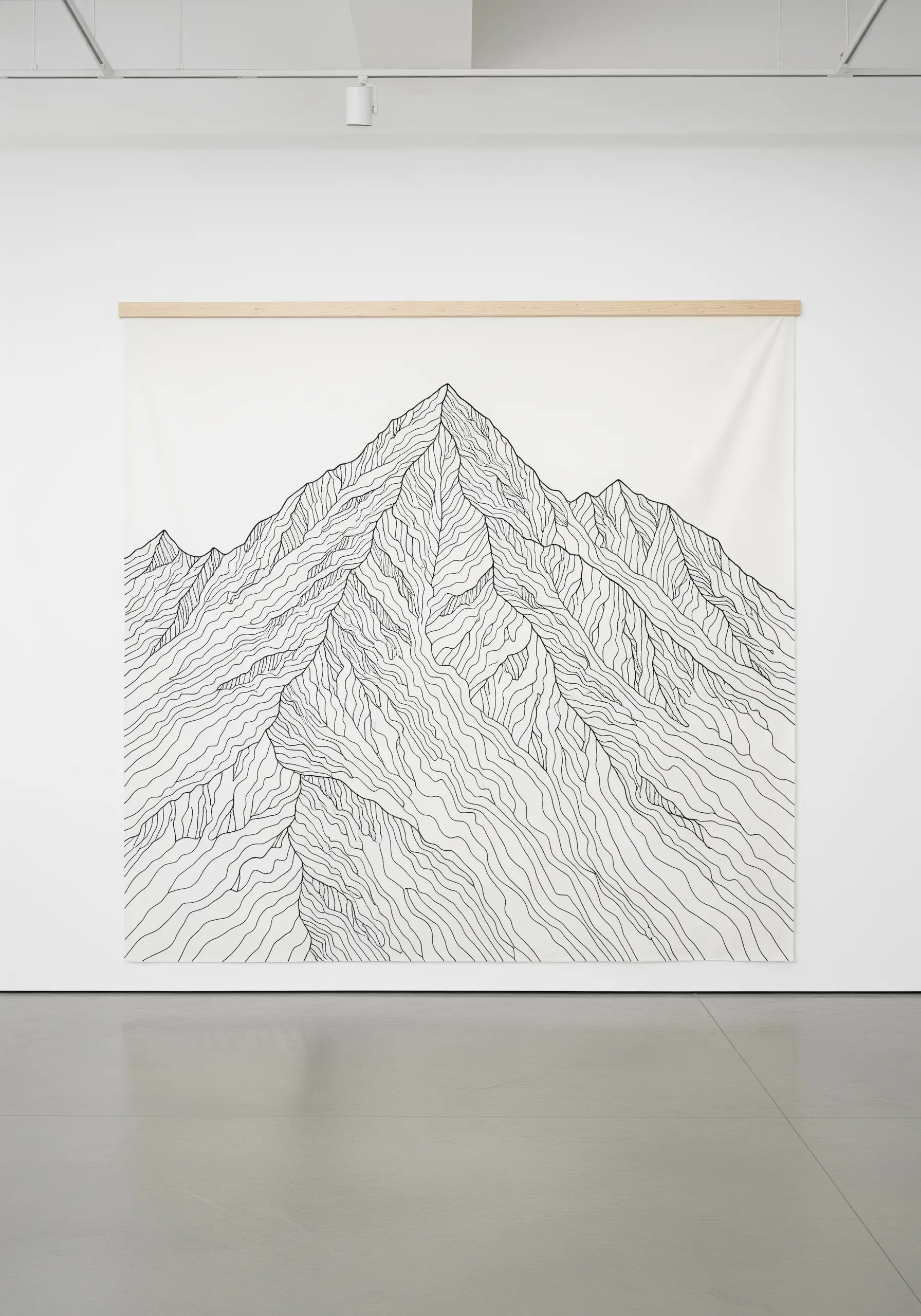 A very large white wall hanging with a complex mountain range rendered in black line embroidery.