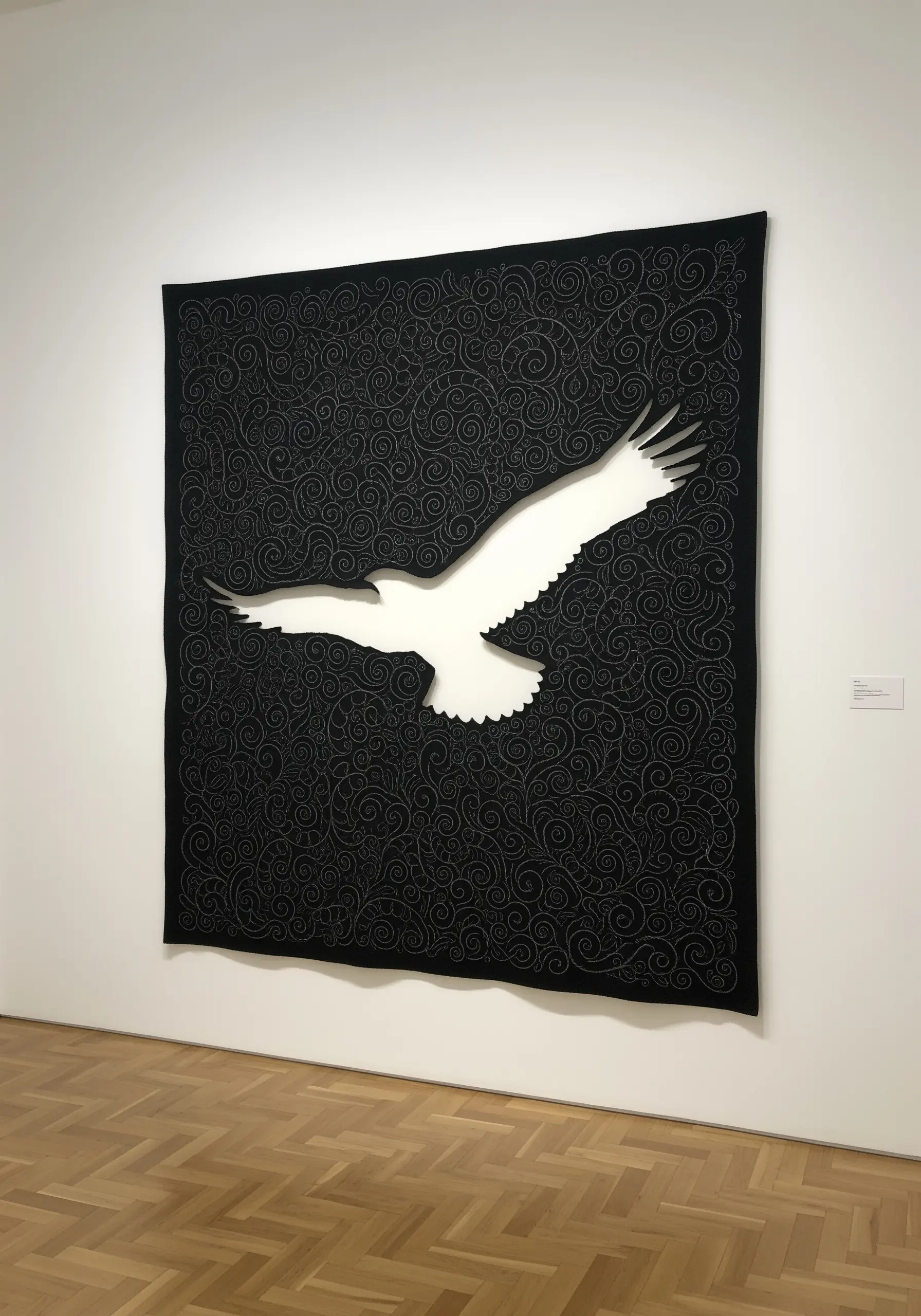 A large black quilted tapestry with swirling gray stitching, leaving the negative space shape of a white eagle.