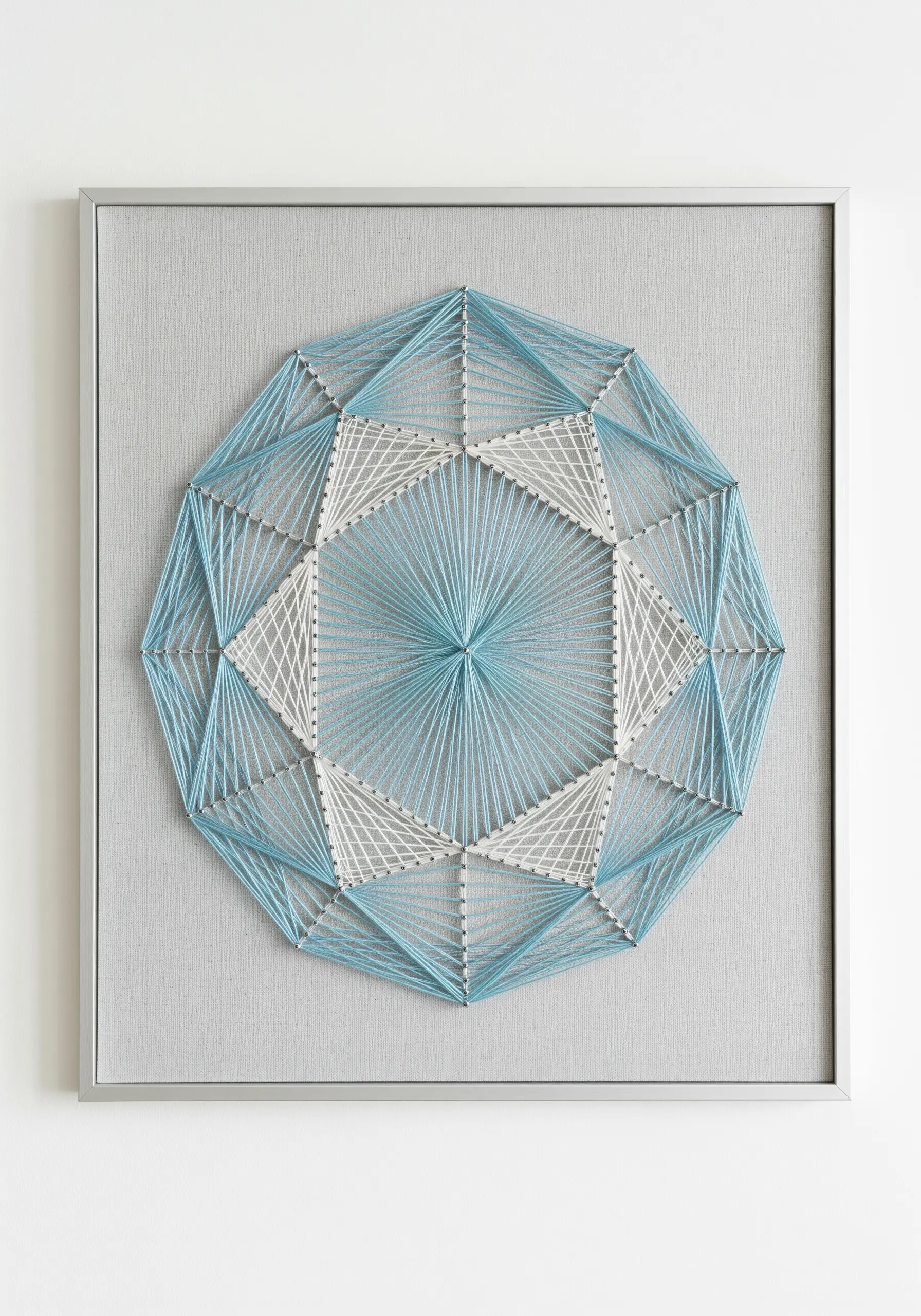 A geometric string art mandala in light blue and white thread, creating layered patterns.