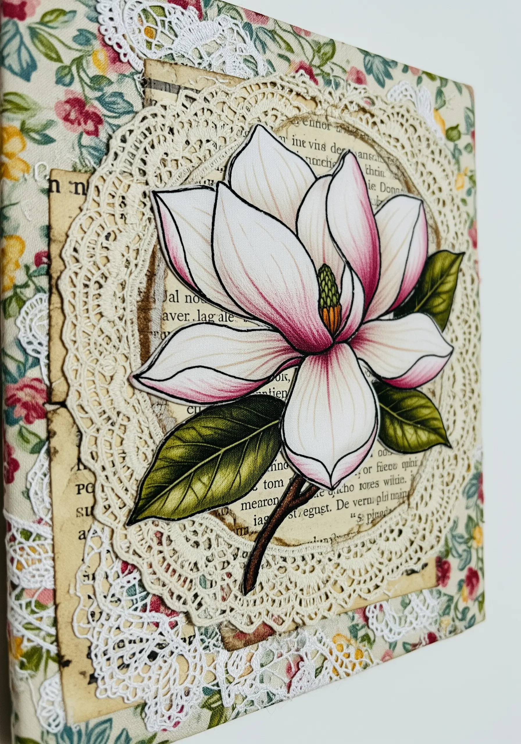 Magnolia motif on a collage of vintage book pages and a lace doily.