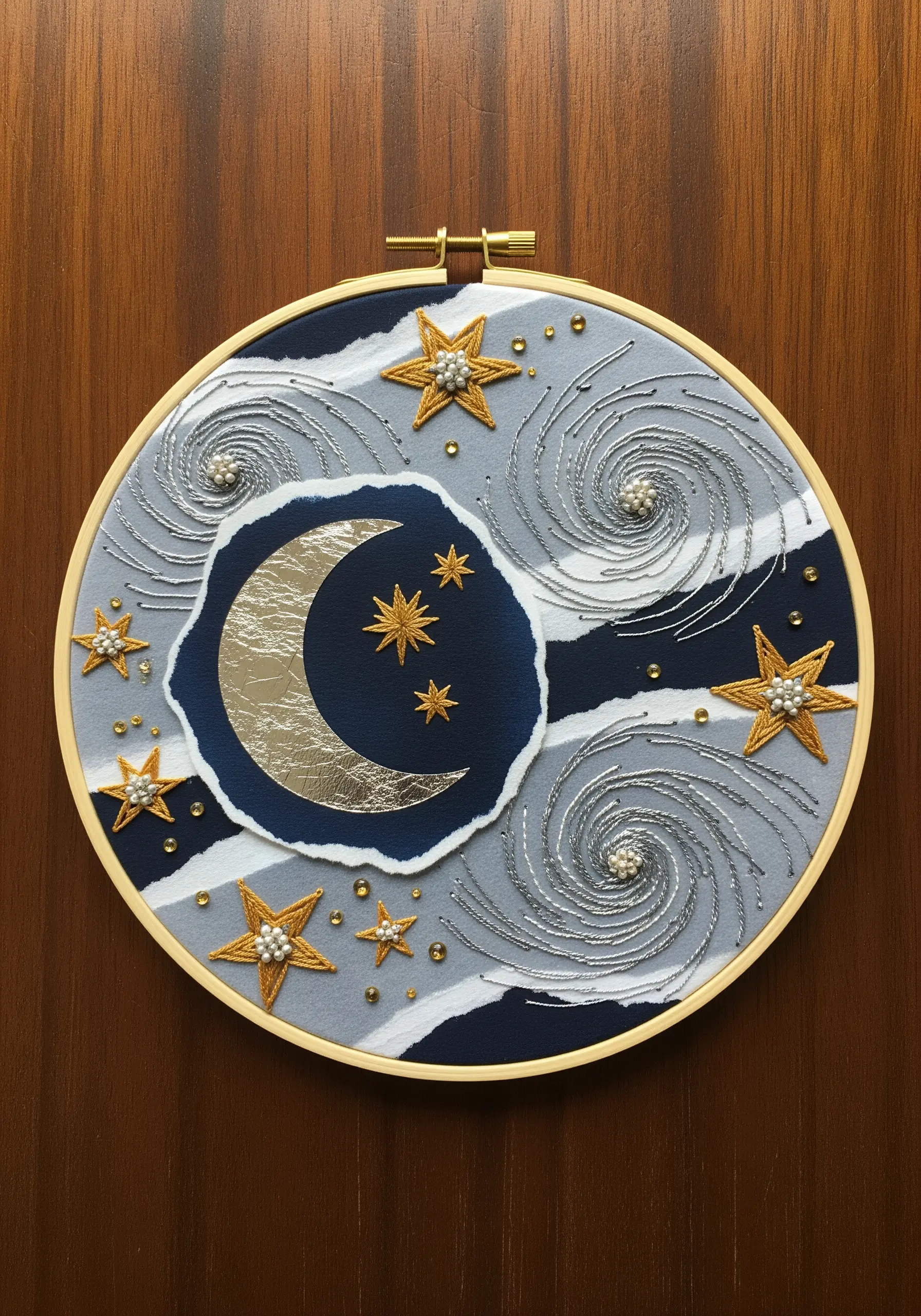 Embroidery hoop with a celestial scene using layered paper, metallic thread, and beads.