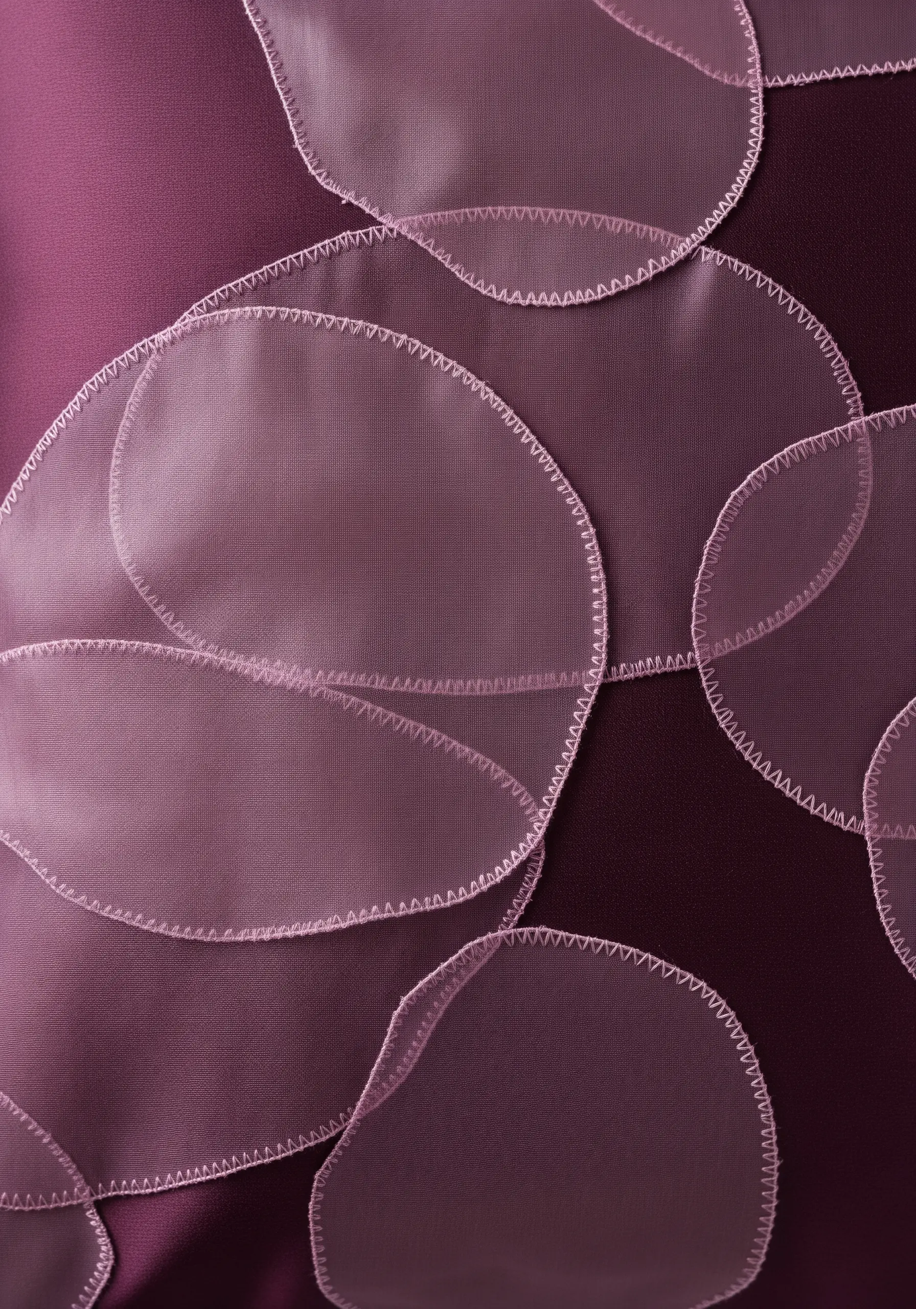 Overlapping circles of sheer pink organza appliquéd onto a dark purple pillow cover.