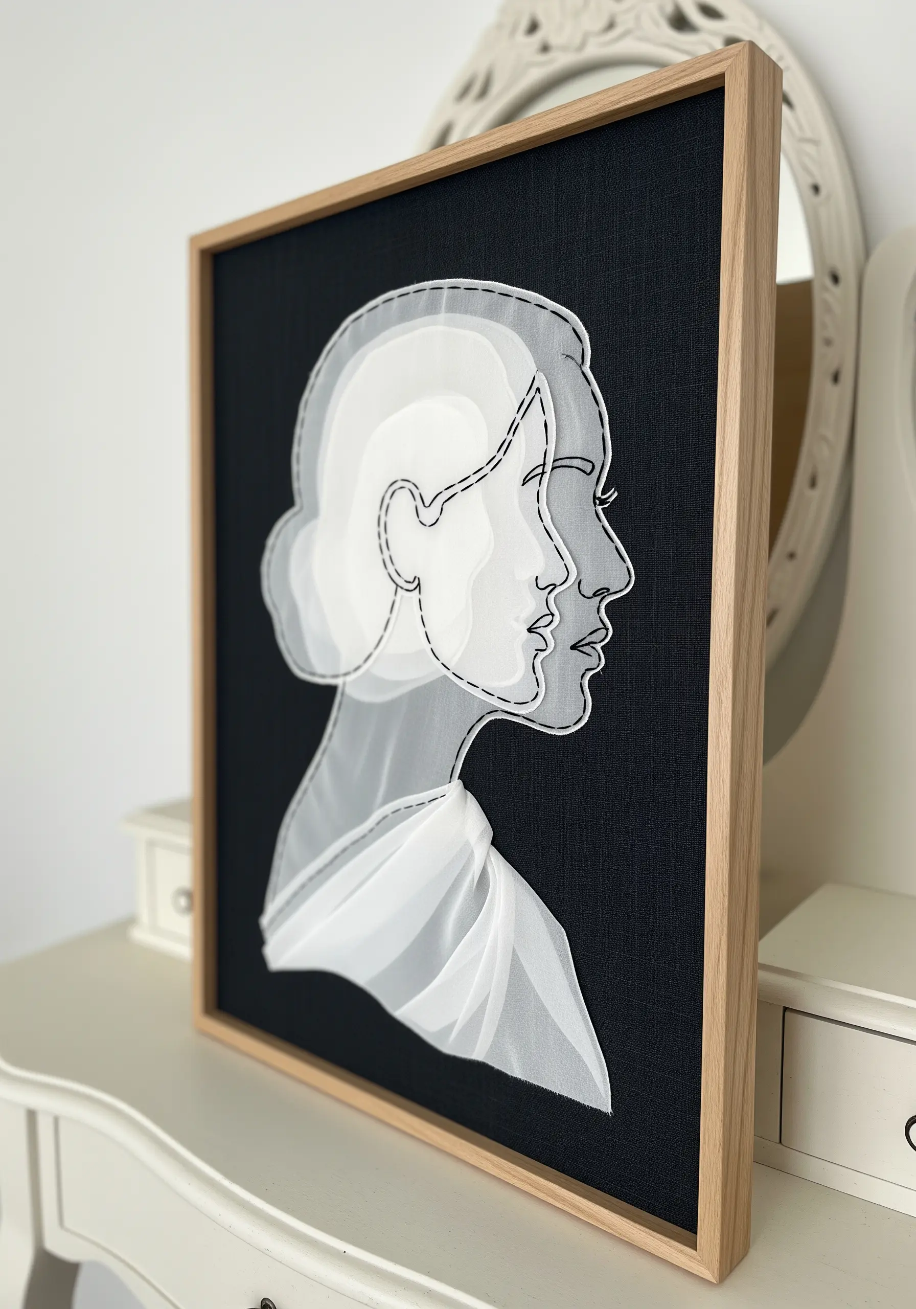 Framed portrait made from layered white sheer fabric on a black background, outlined with stitching.