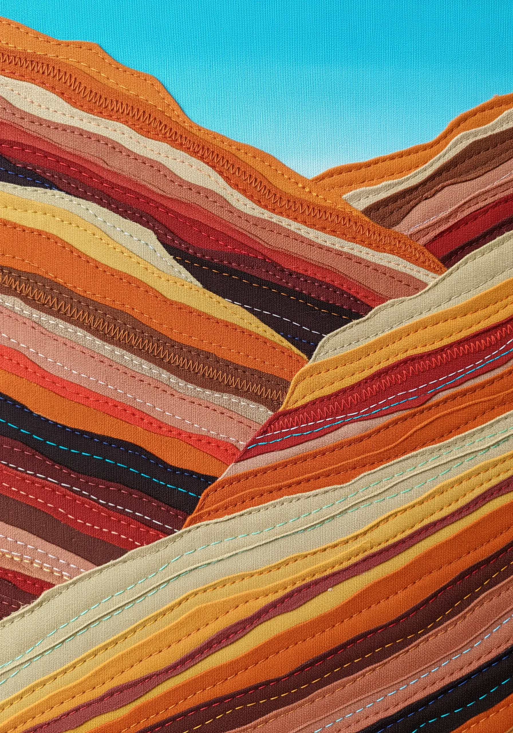 Abstract landscape made from layered fabric strips with decorative machine stitching.