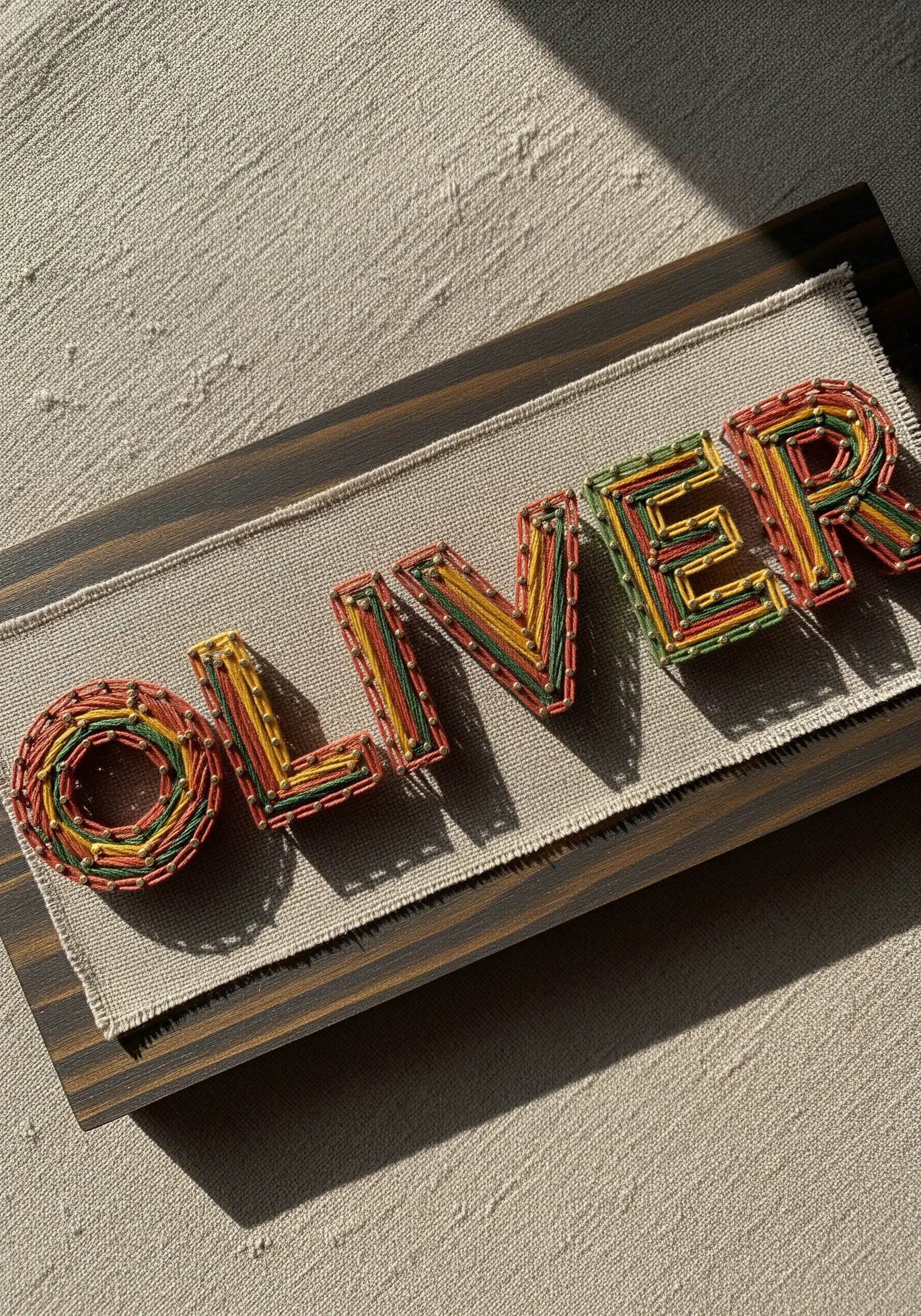Embroidery name with densely layered variegated thread in warm earth tones.