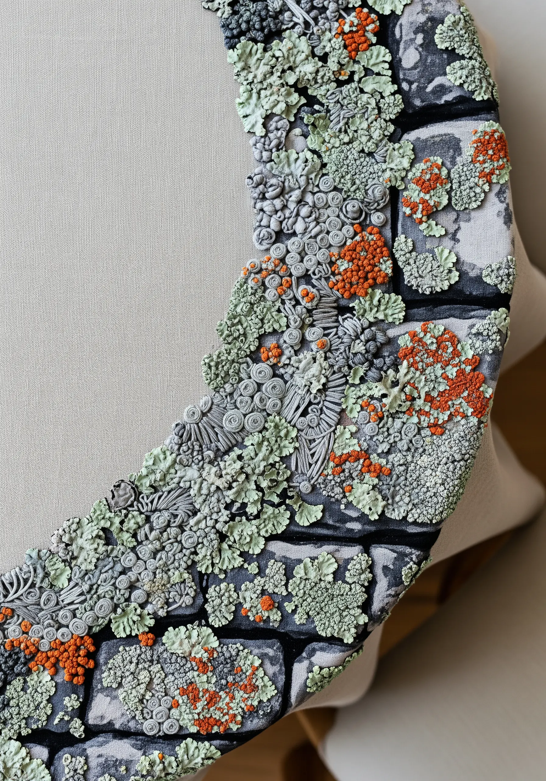 Close-up of a hoop with highly textured lichen embroidered onto a stone-printed fabric.