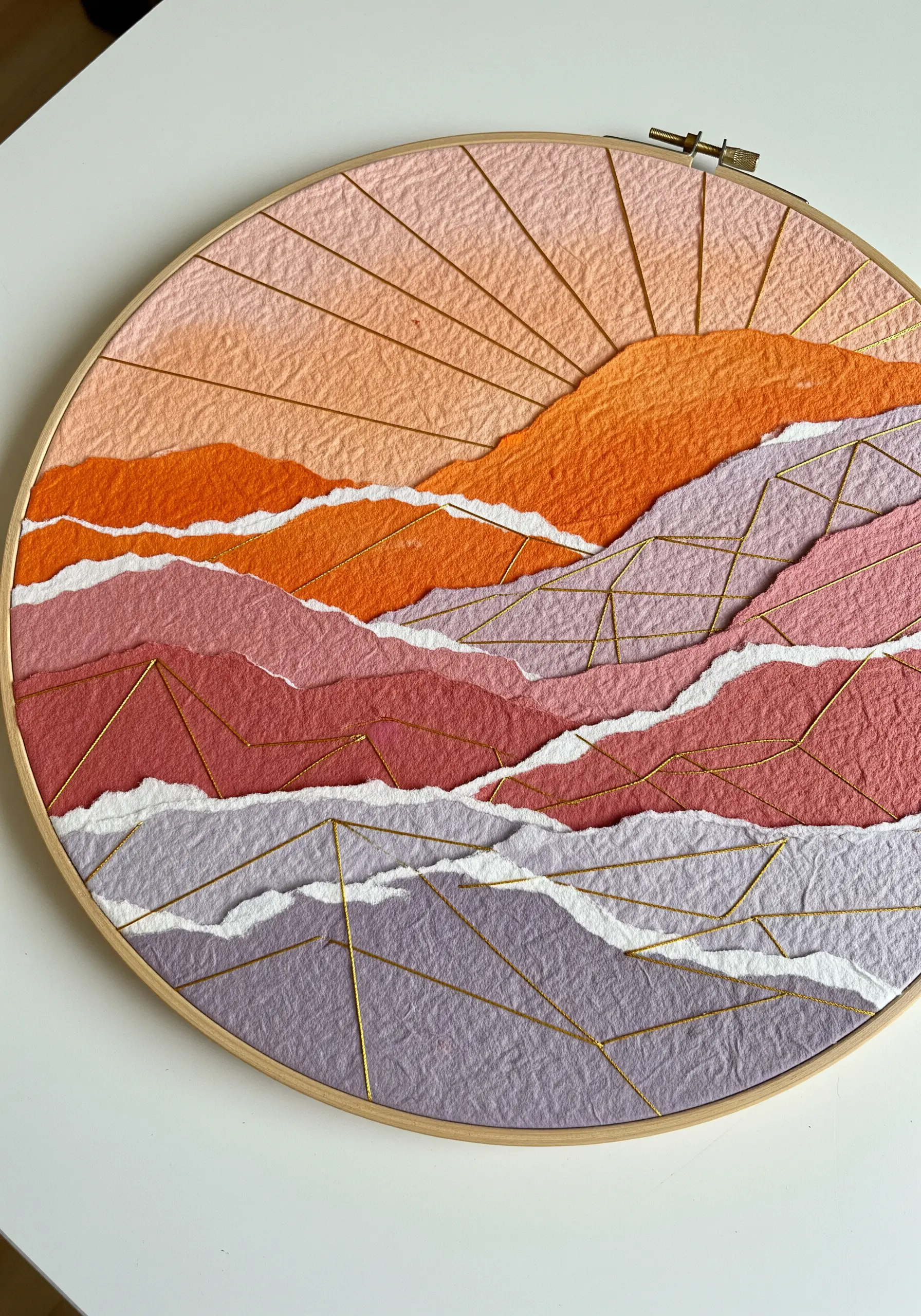 Torn paper mountain landscape in a hoop, accented with gold geometric thread lines.