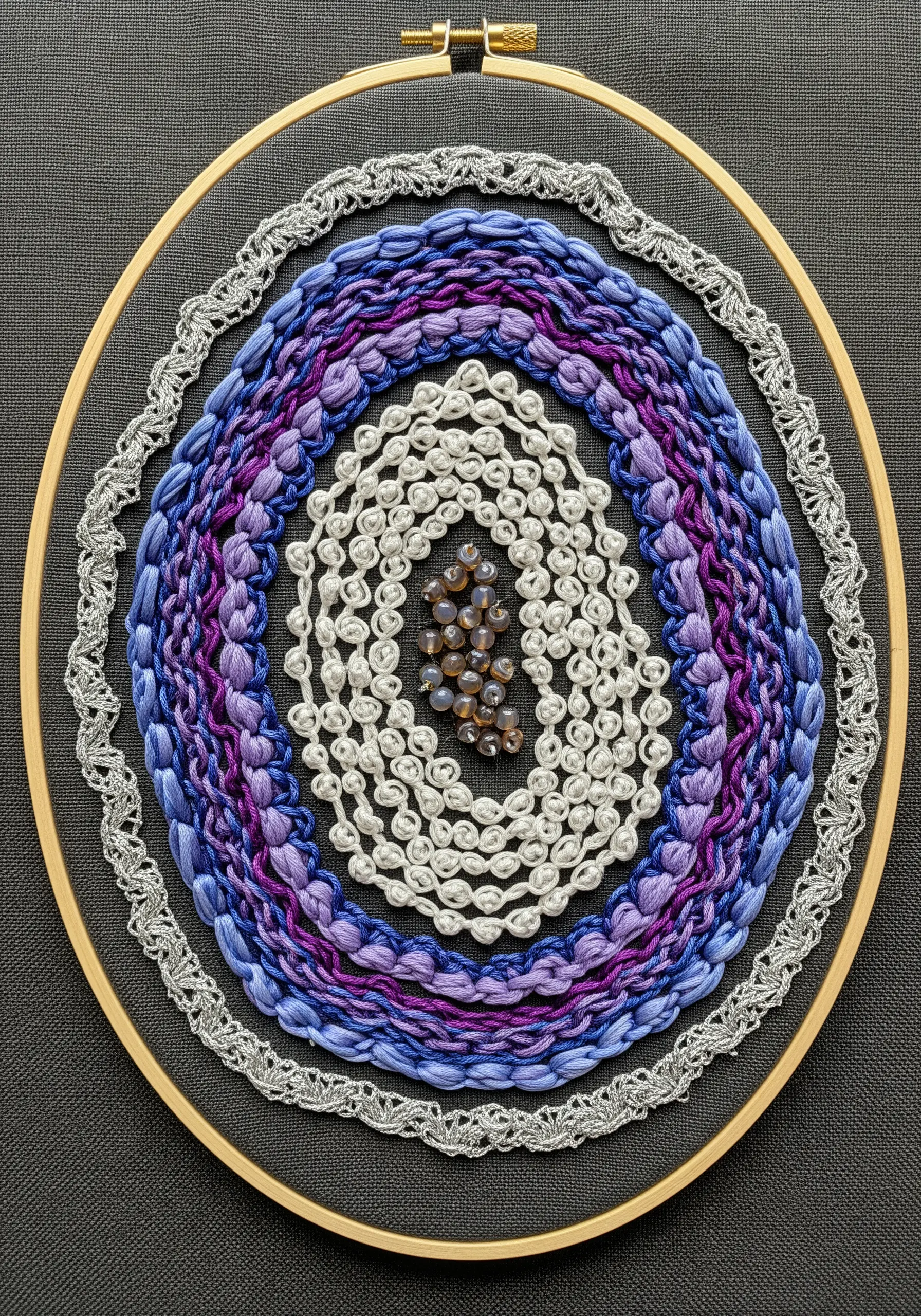 A richly textured mandala with concentric rings of blue and purple stitches, white beads, and metallic thread.