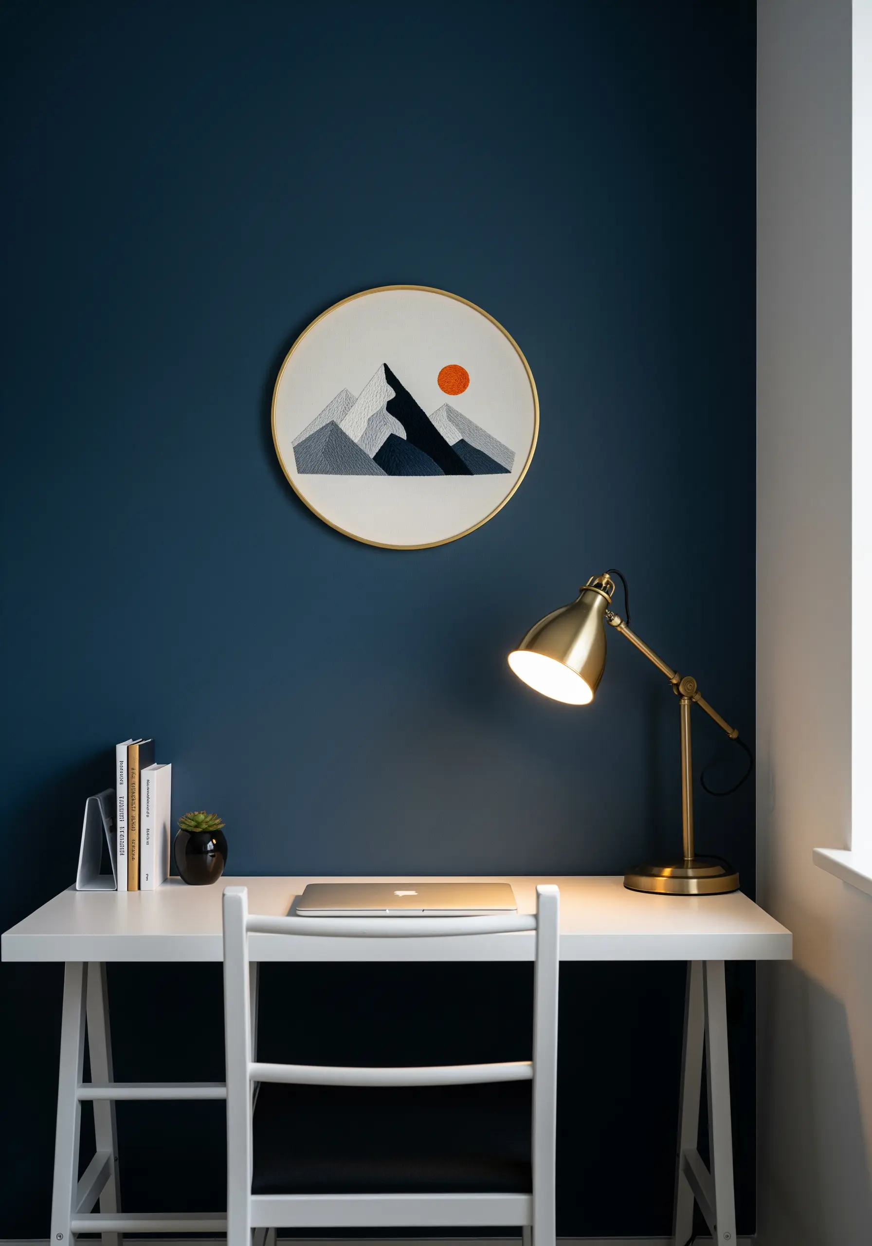 Embroidered mountain landscape with layered grey tones and a small orange sun.