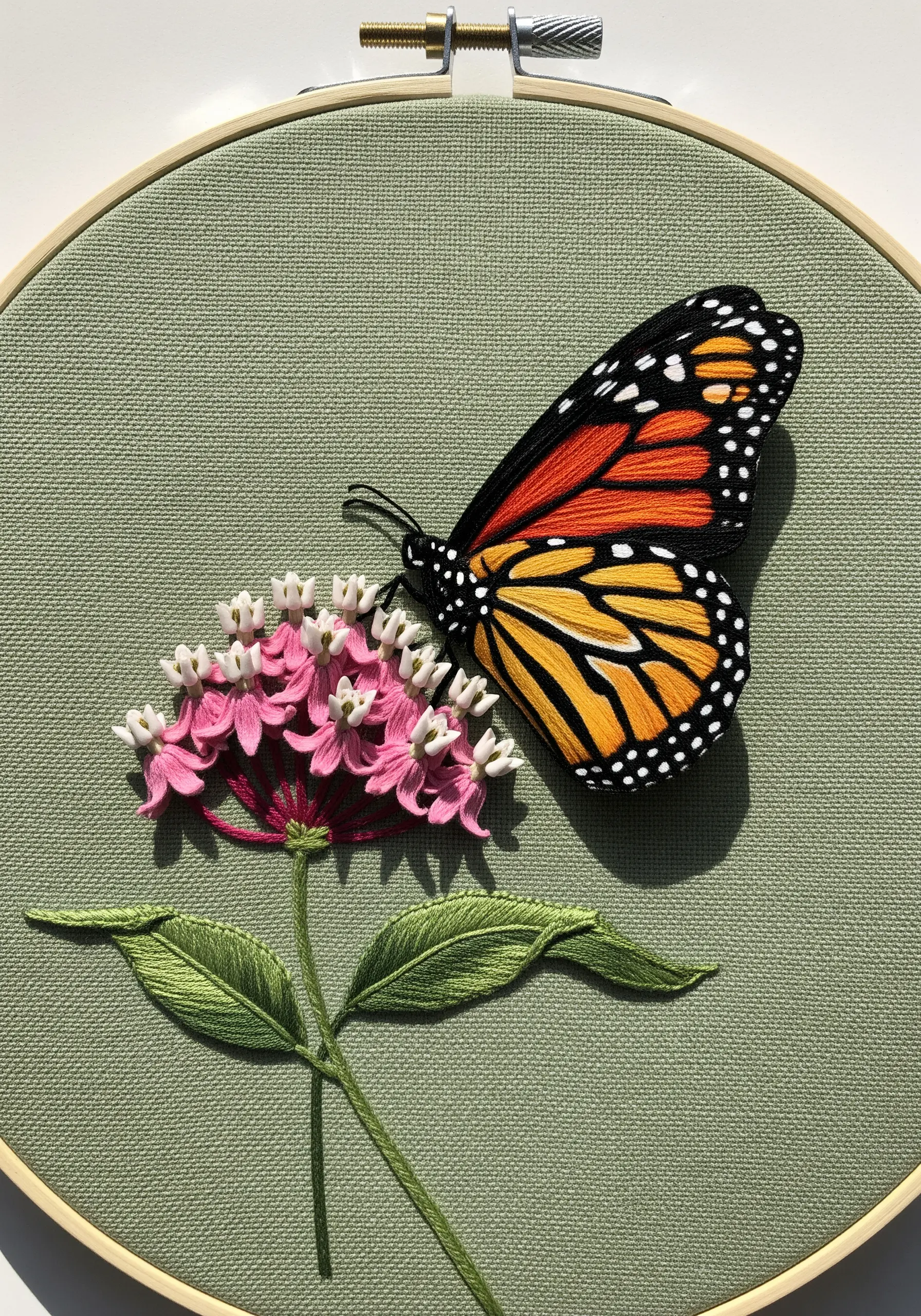 A realistic, 3D embroidered monarch butterfly with raised wings on a flower.