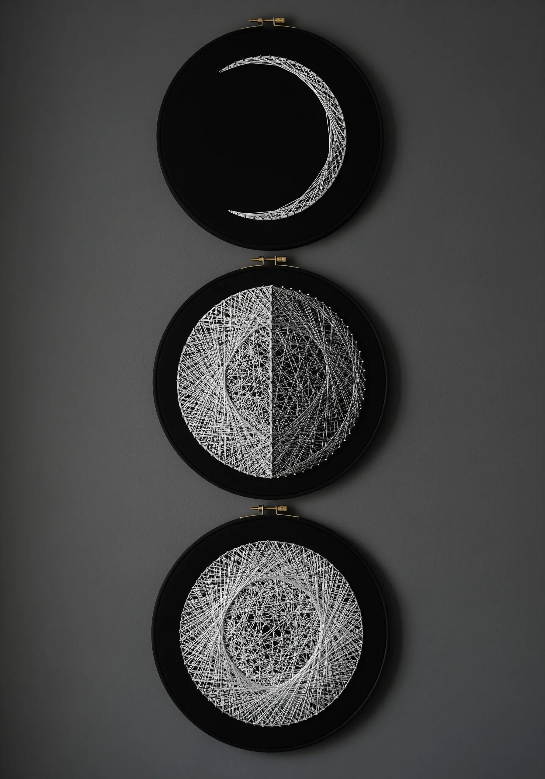 A triptych of embroidered moon phases in black hoops, showing different thread densities.