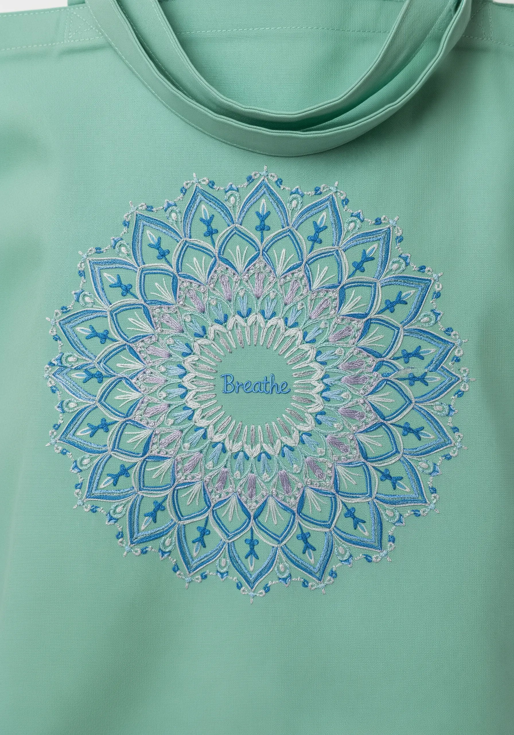 A detailed blue and purple embroidered mandala with the word 'Breathe' in the center.