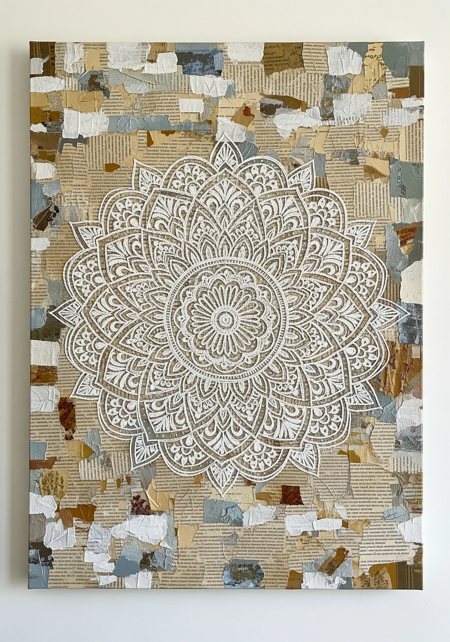An intricate white paper mandala placed over a neutral-toned collage of torn book pages.