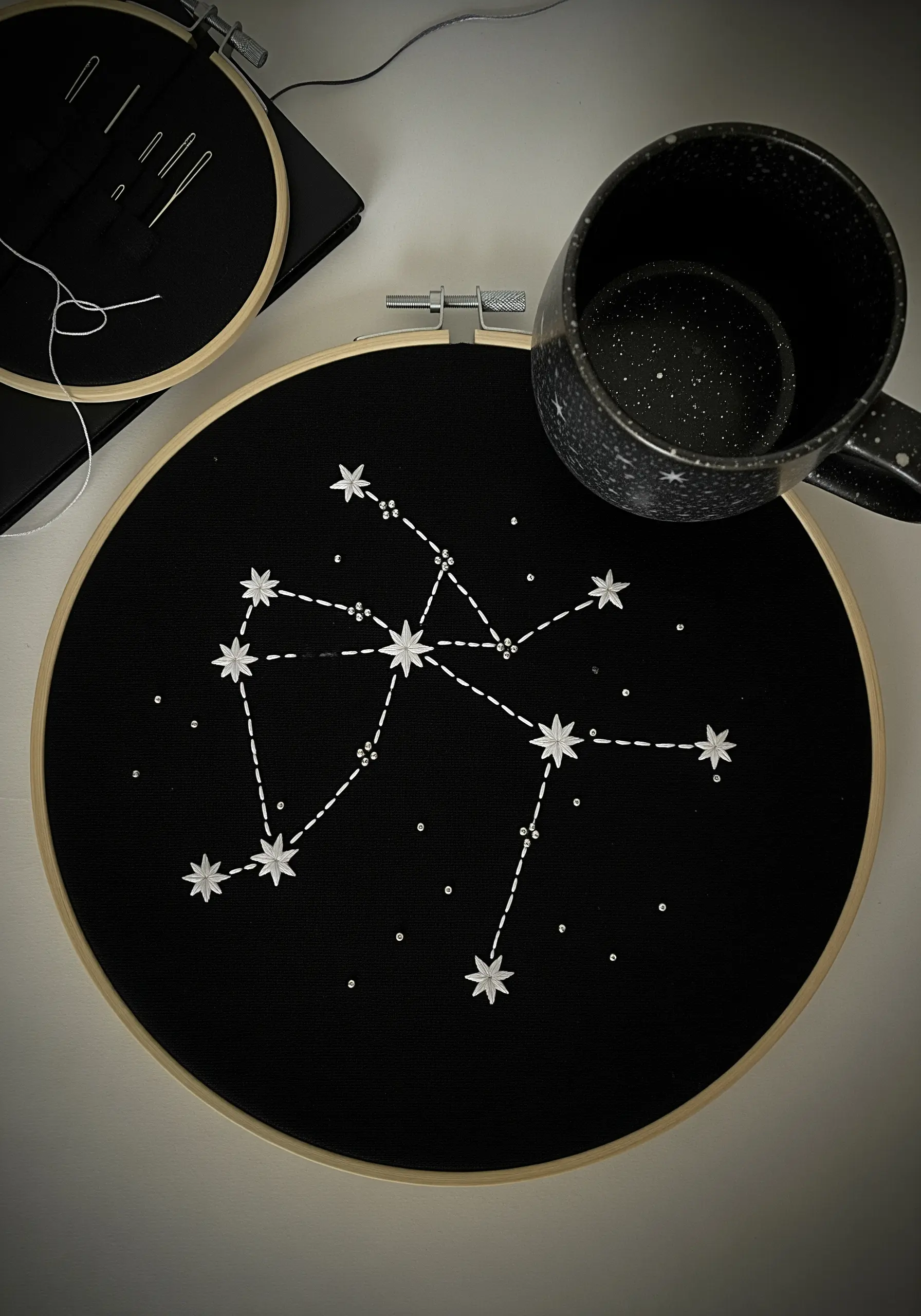 An embroidered constellation on black fabric, accented with tiny silver beads for sparkle.