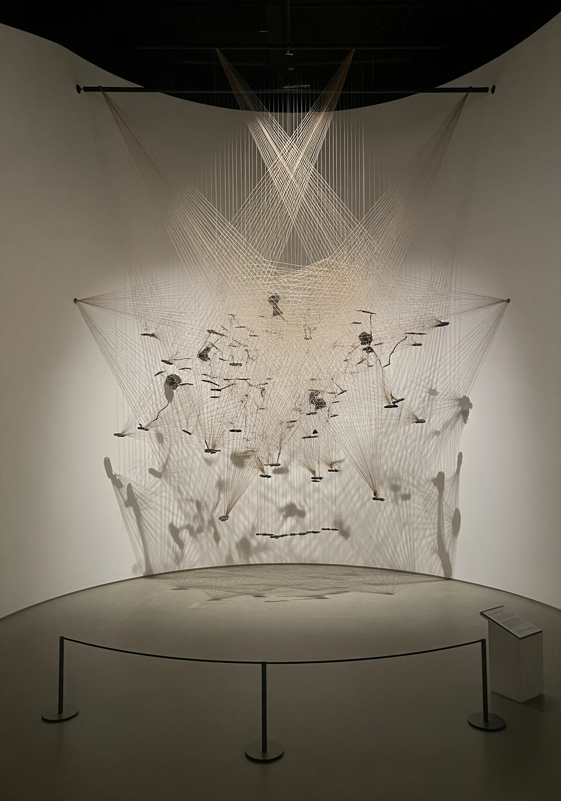 A complex thread art installation connecting small suspended objects, creating a star map.