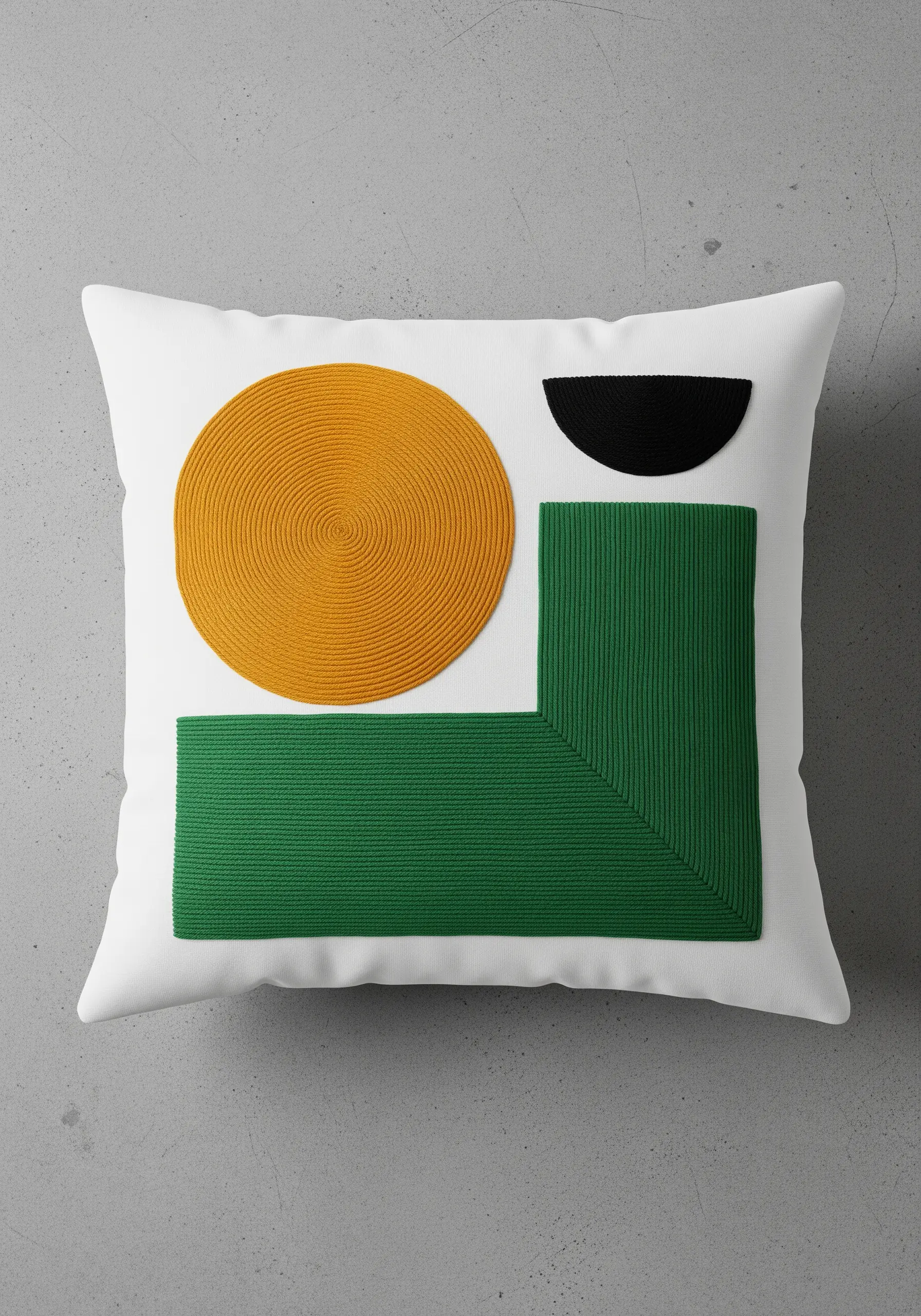 A white pillow with bold geometric shapes in yellow, green, and black, created with corded texture.
