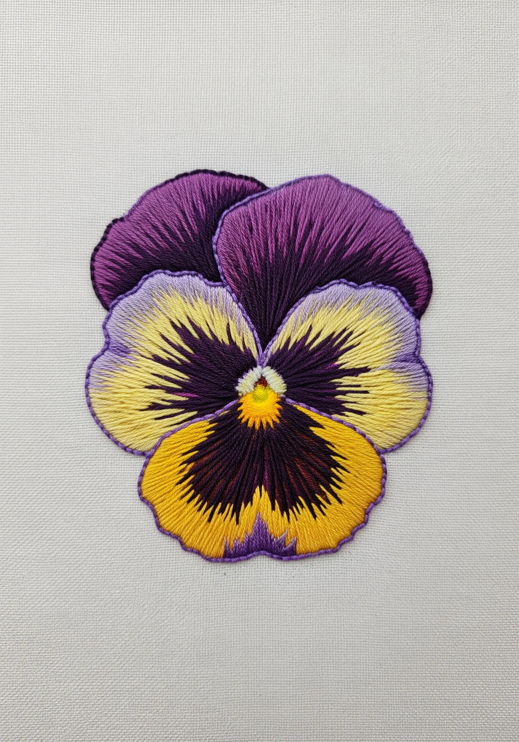 A realistic pansy embroidered with detailed thread painting in purple, yellow, and black.
