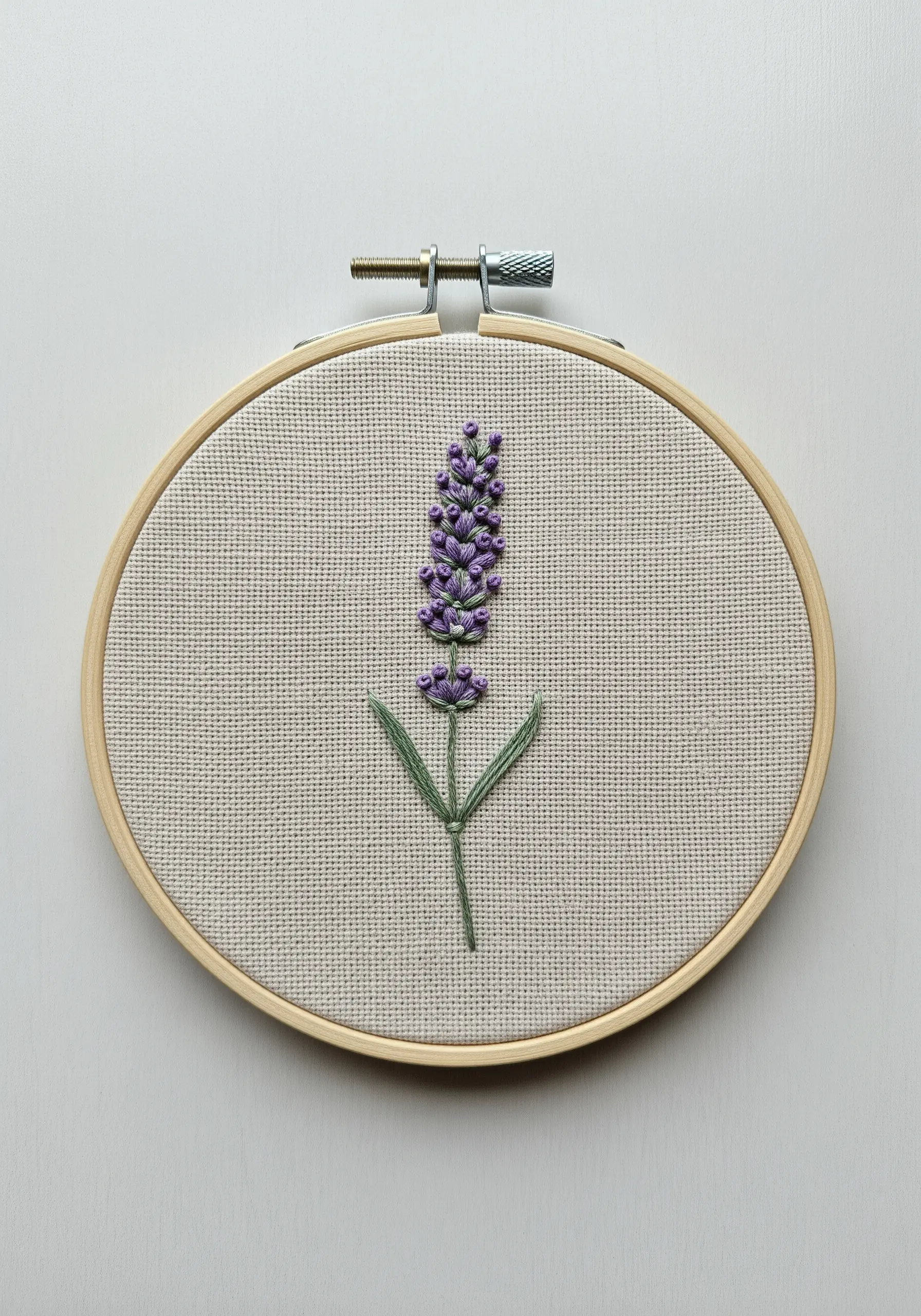 Lavender embroidery with purple French knots and a green stem in a wooden hoop.