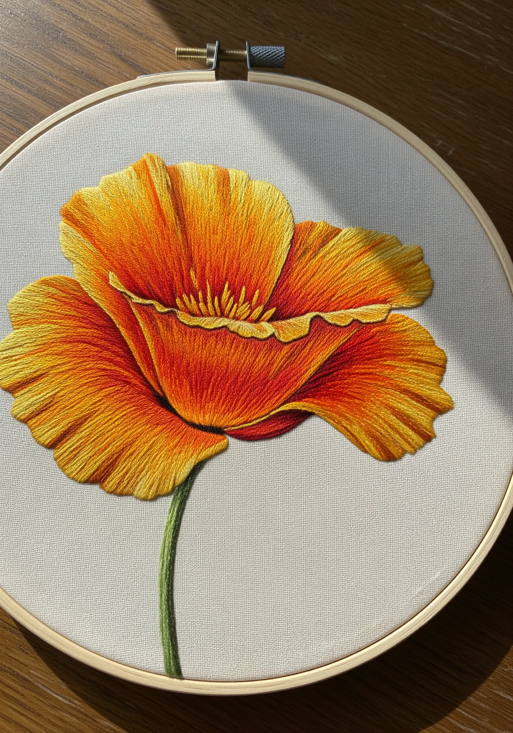 Thread-painted orange poppy showcasing realistic color blending and directional stitches.