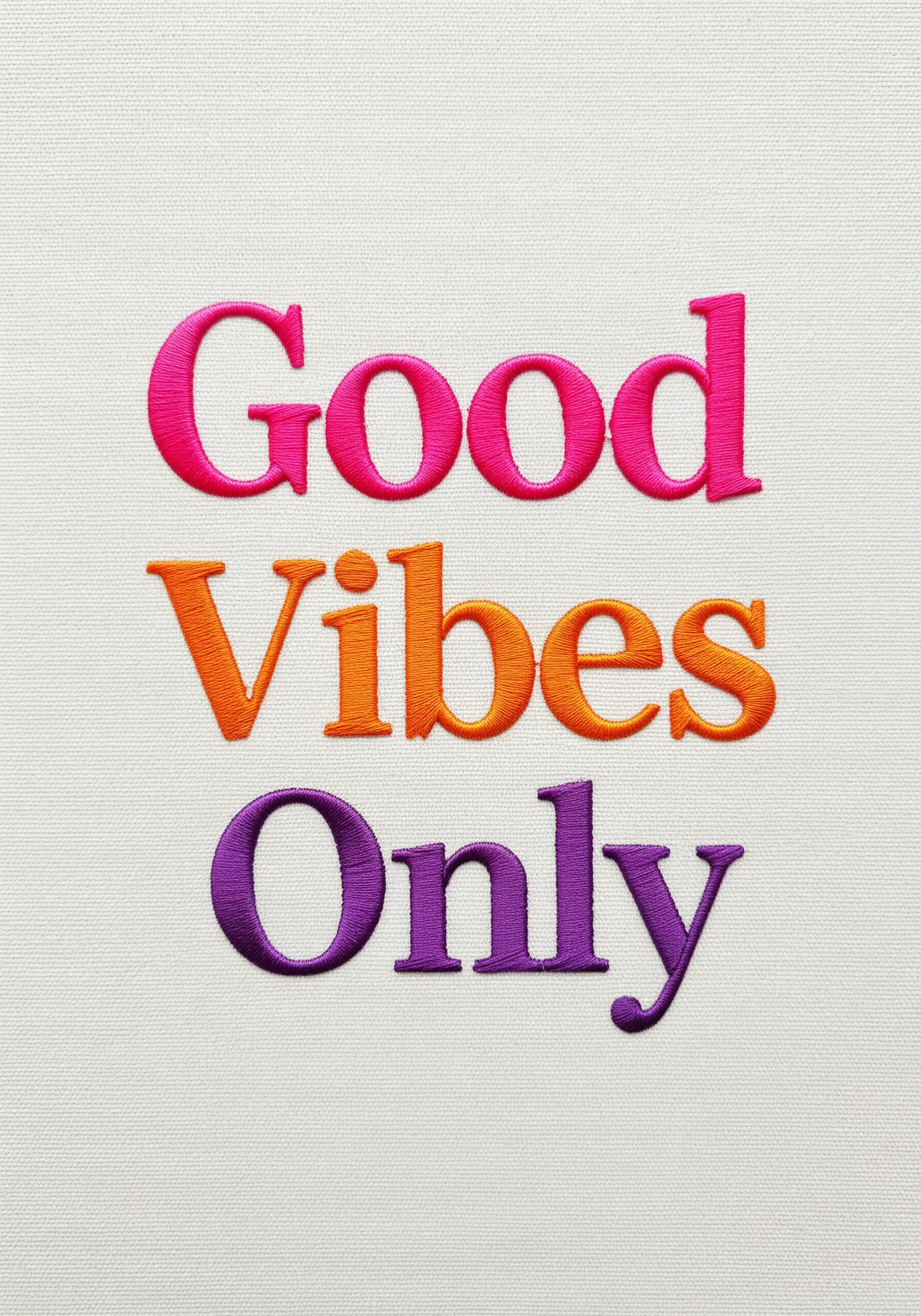 Flawless satin stitch typography in pink, orange, and purple on white fabric.