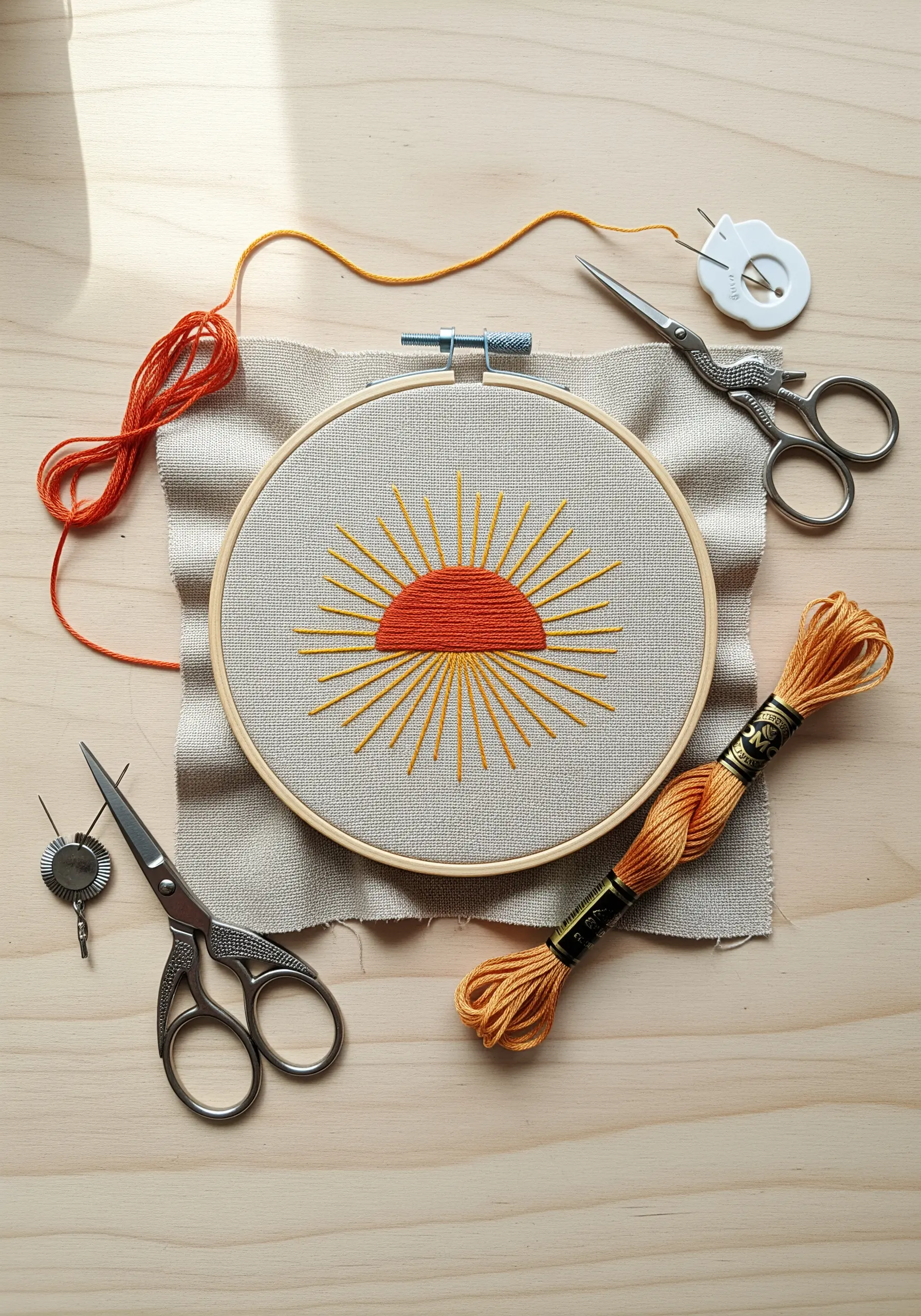 A minimal embroidered sun with orange satin stitch and yellow radiating lines.
