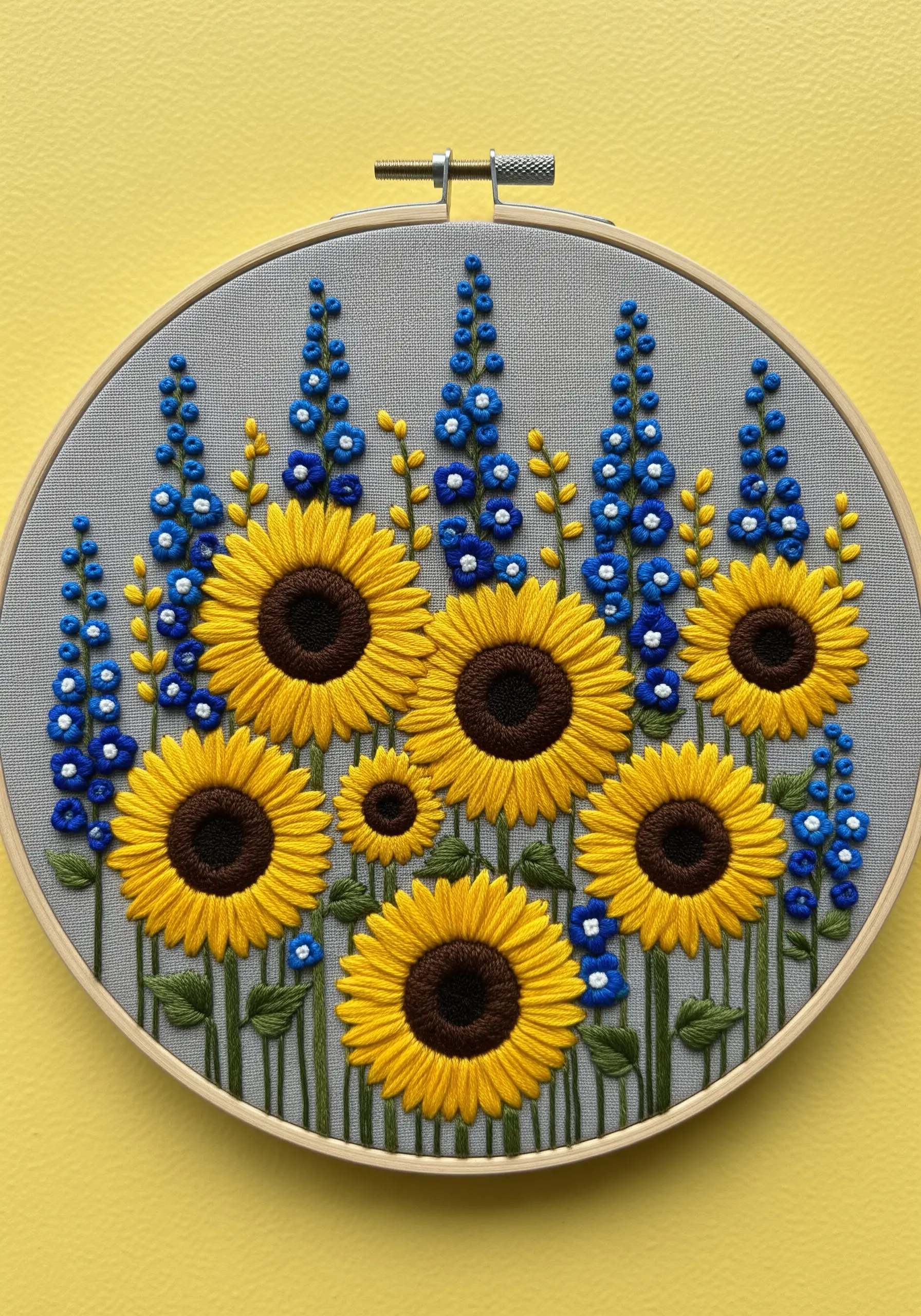 Bright yellow sunflowers and deep blue delphiniums embroidered on a grey background.