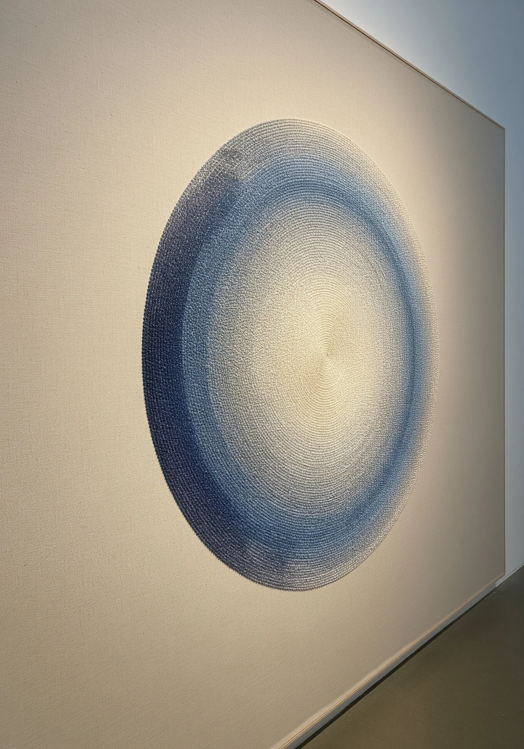 A large, circular gradient of blue to white, made with thousands of tiny stitches.