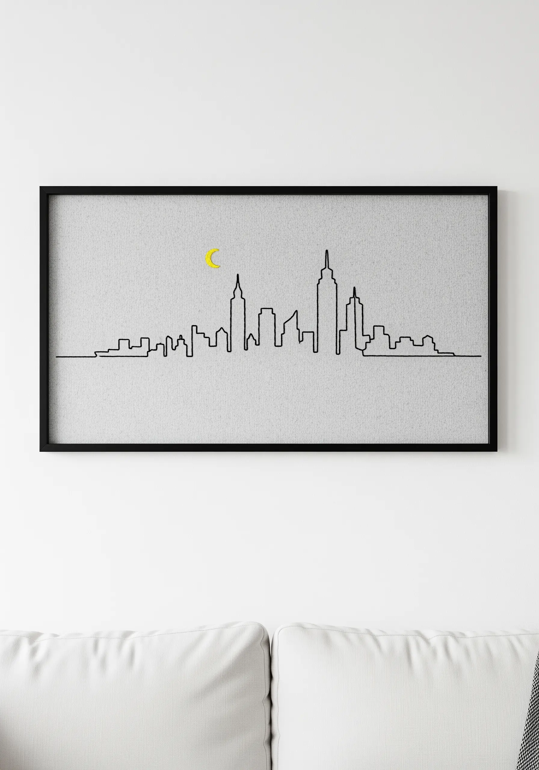 A minimal black line embroidery of a city skyline with a small yellow crescent moon.