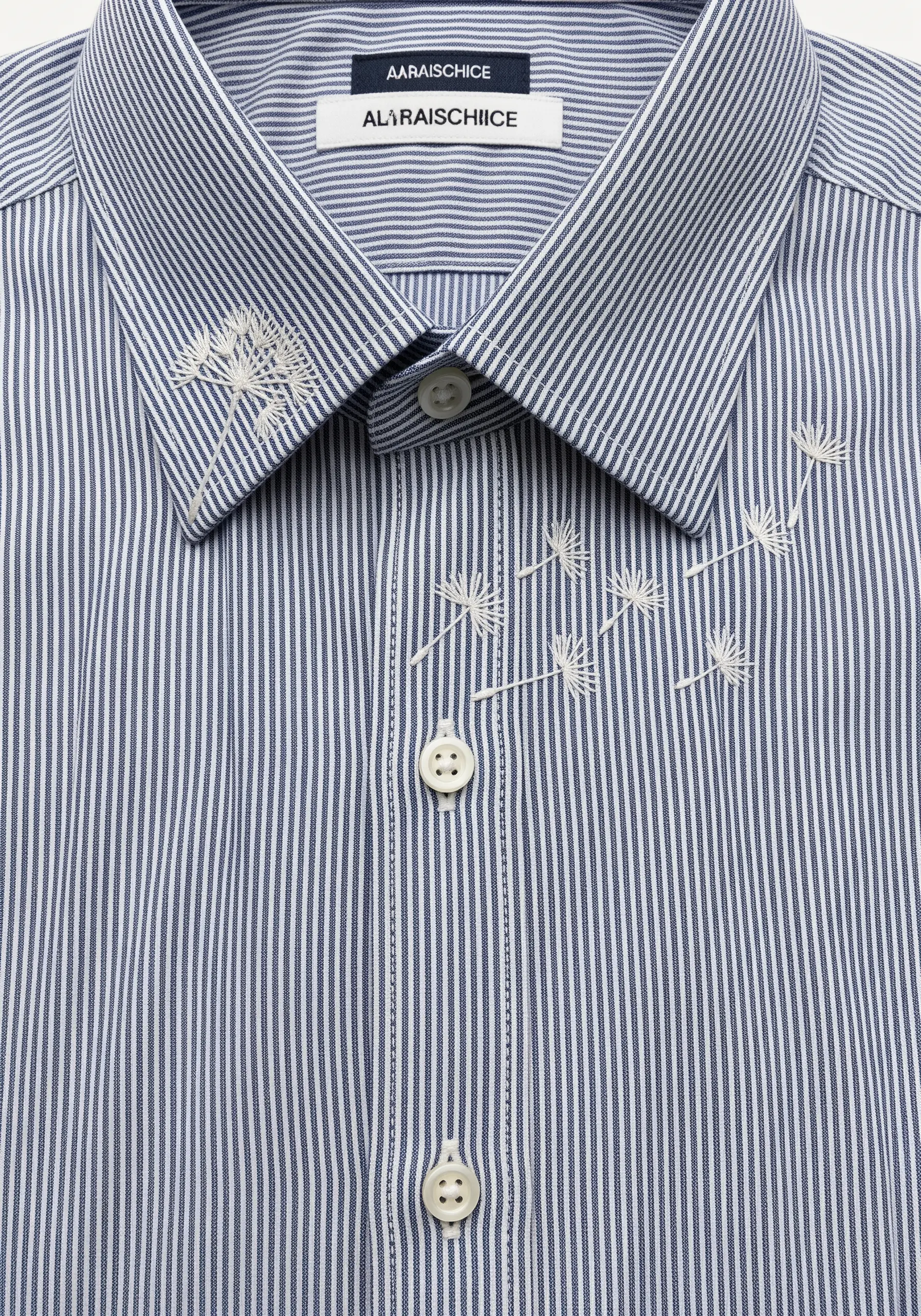 Delicate white dandelion seeds embroidered as if floating across a striped blue shirt.