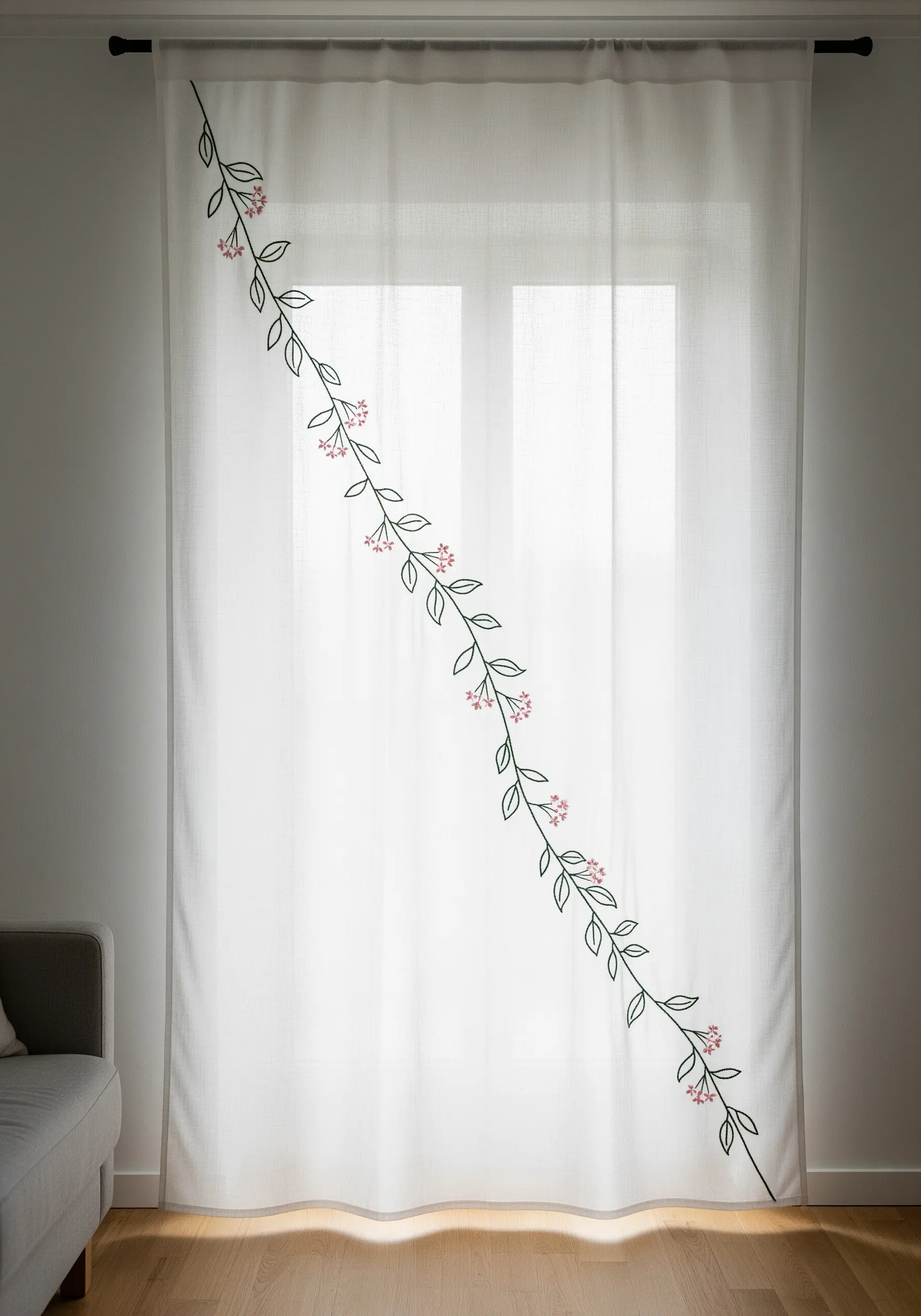 A single, delicate vine embroidered diagonally across a sheer white curtain panel.