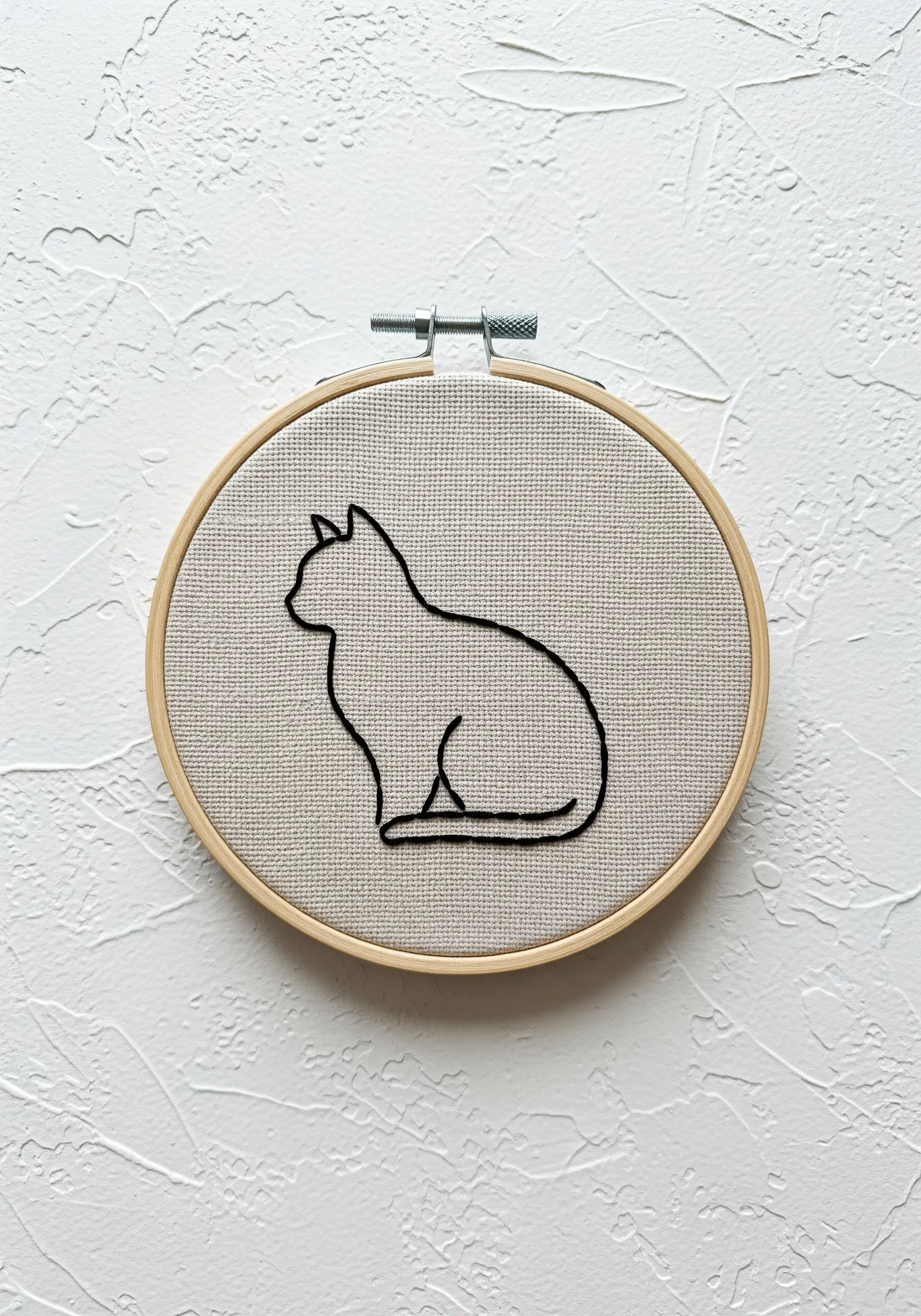 Minimalist black line embroidery of a seated cat silhouette on linen