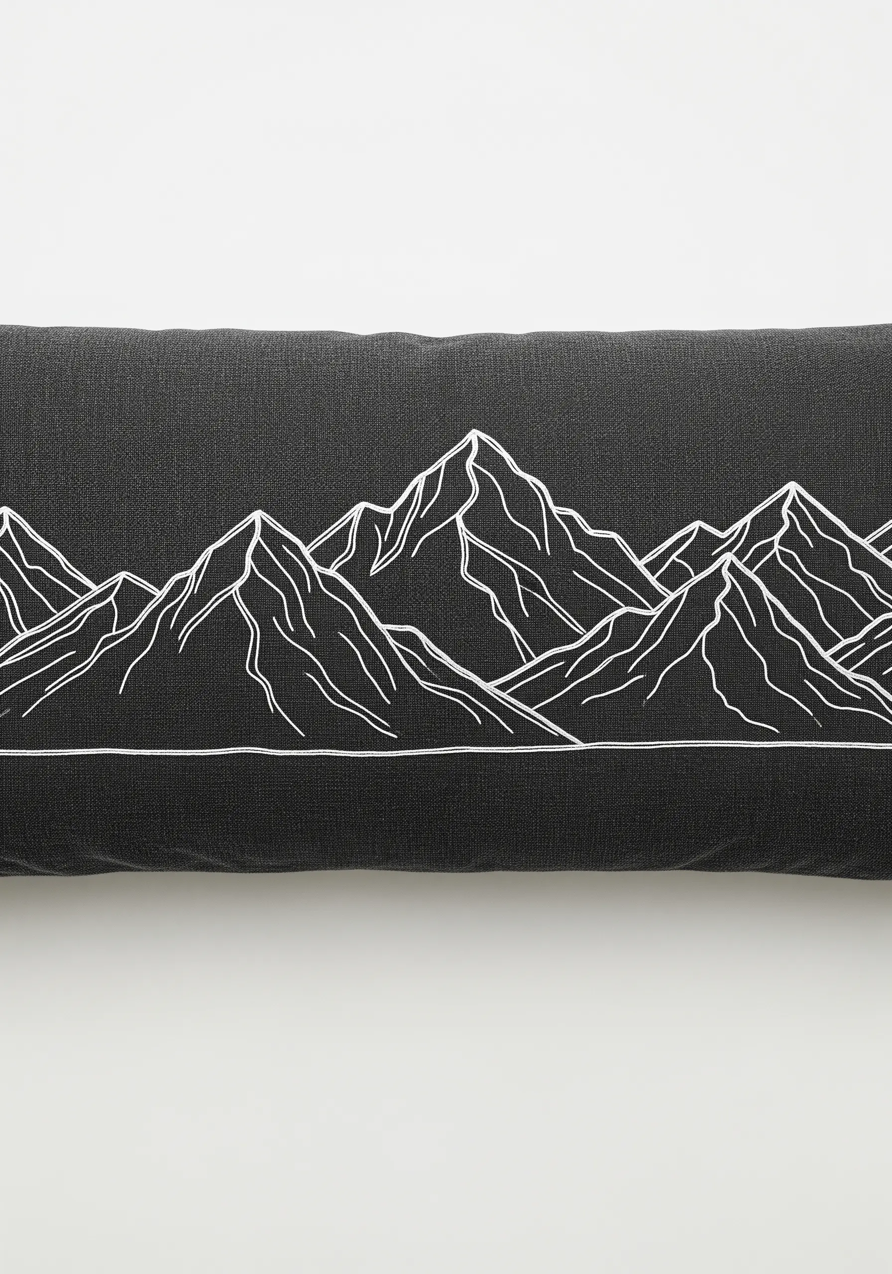 A simple white line art embroidery of a mountain range on a dark gray lumbar pillow.