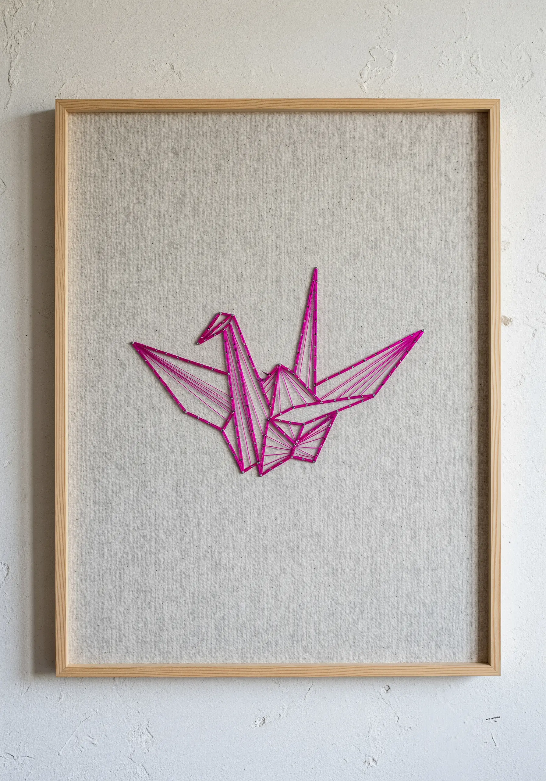 A minimalist neon pink origami crane stitched on a light neutral canvas.