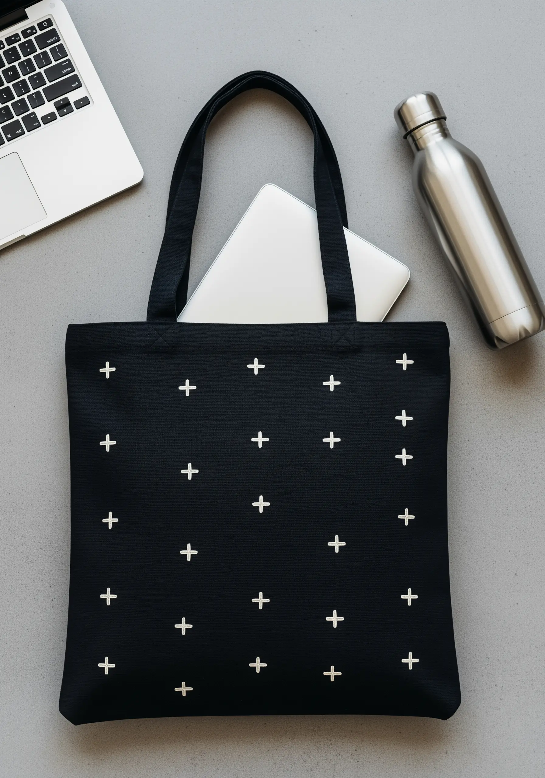 A repeating grid pattern of small white embroidered plus signs on a black tote bag.