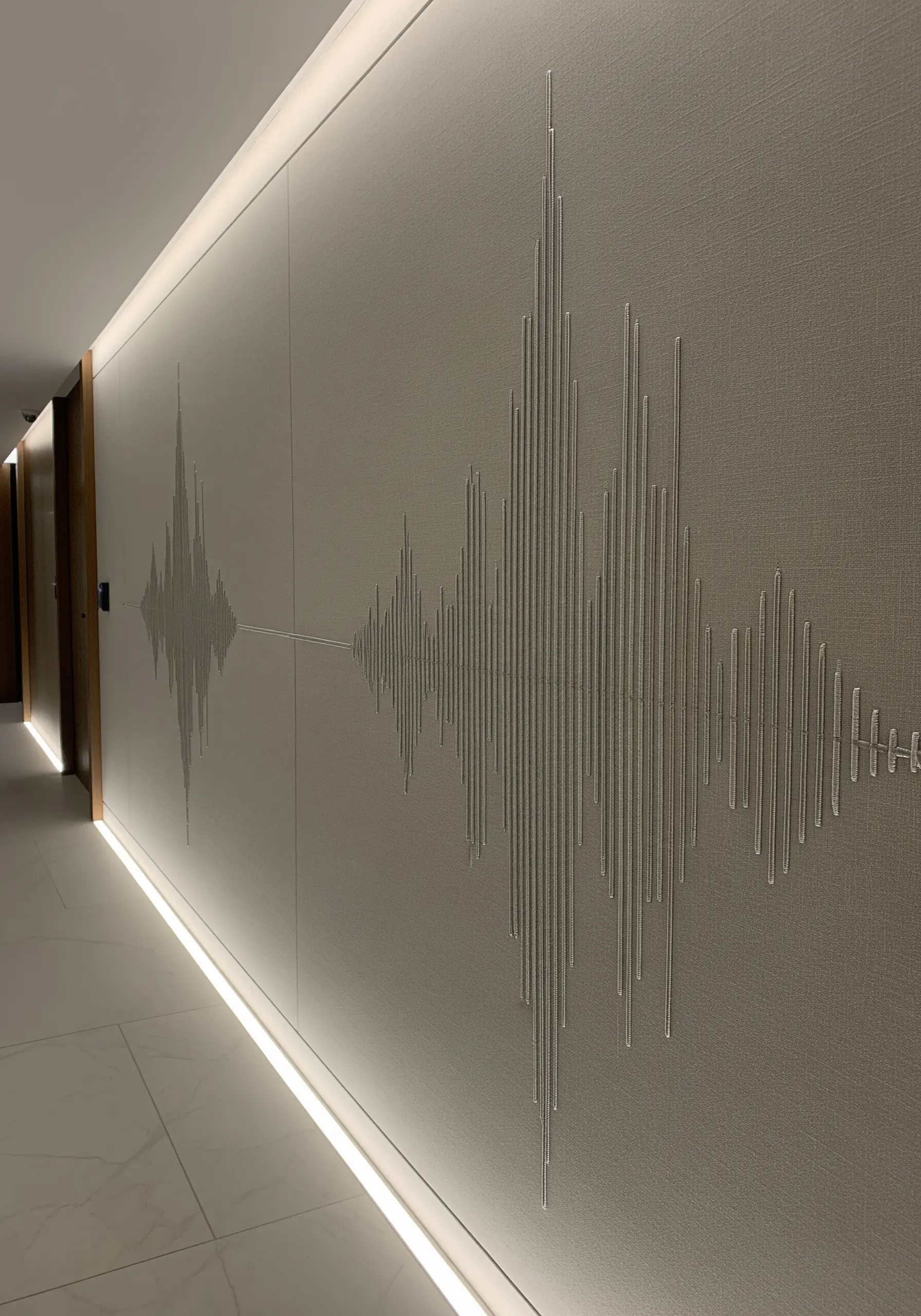 A long wall with a minimalist soundwave pattern embroidered in silver thread.