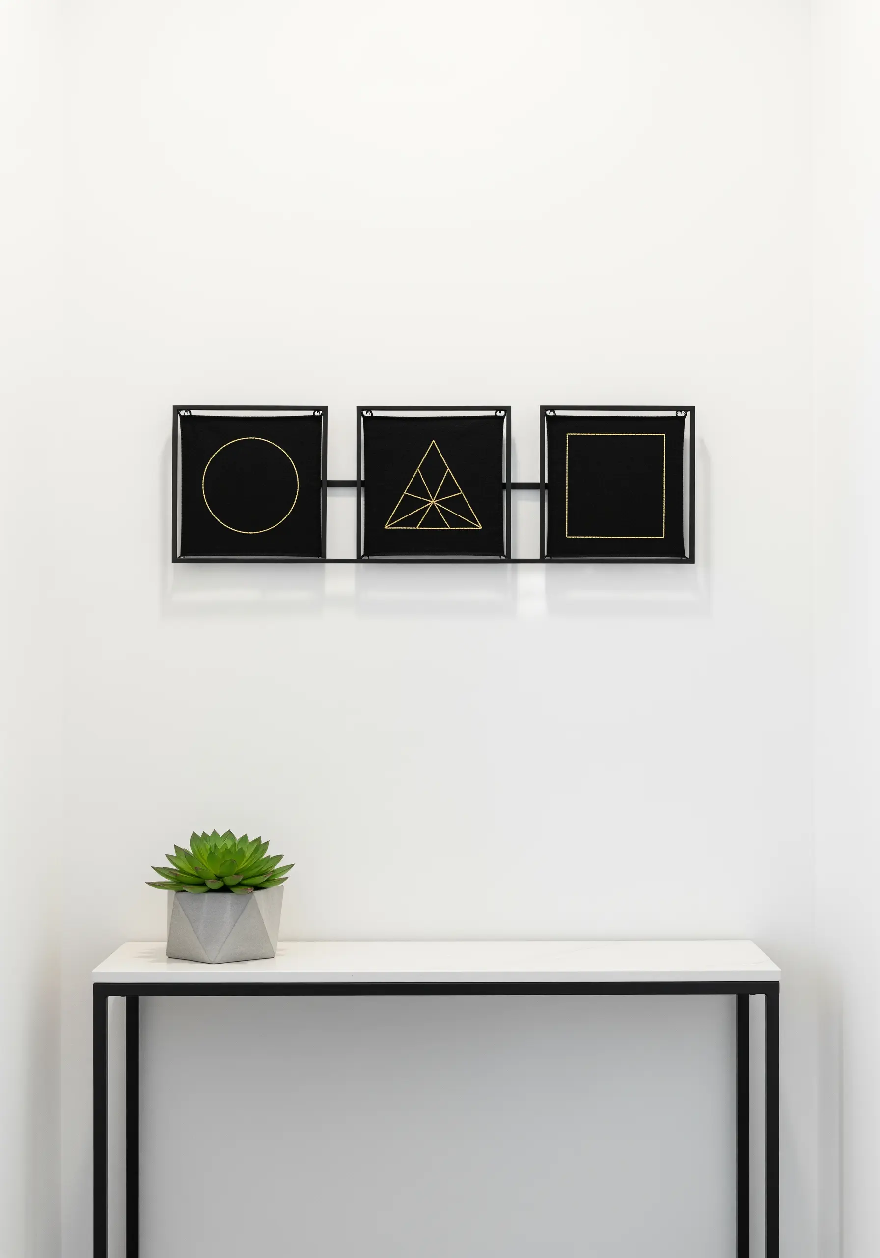 Gold metallic thread embroidered in geometric shapes on black fabric.