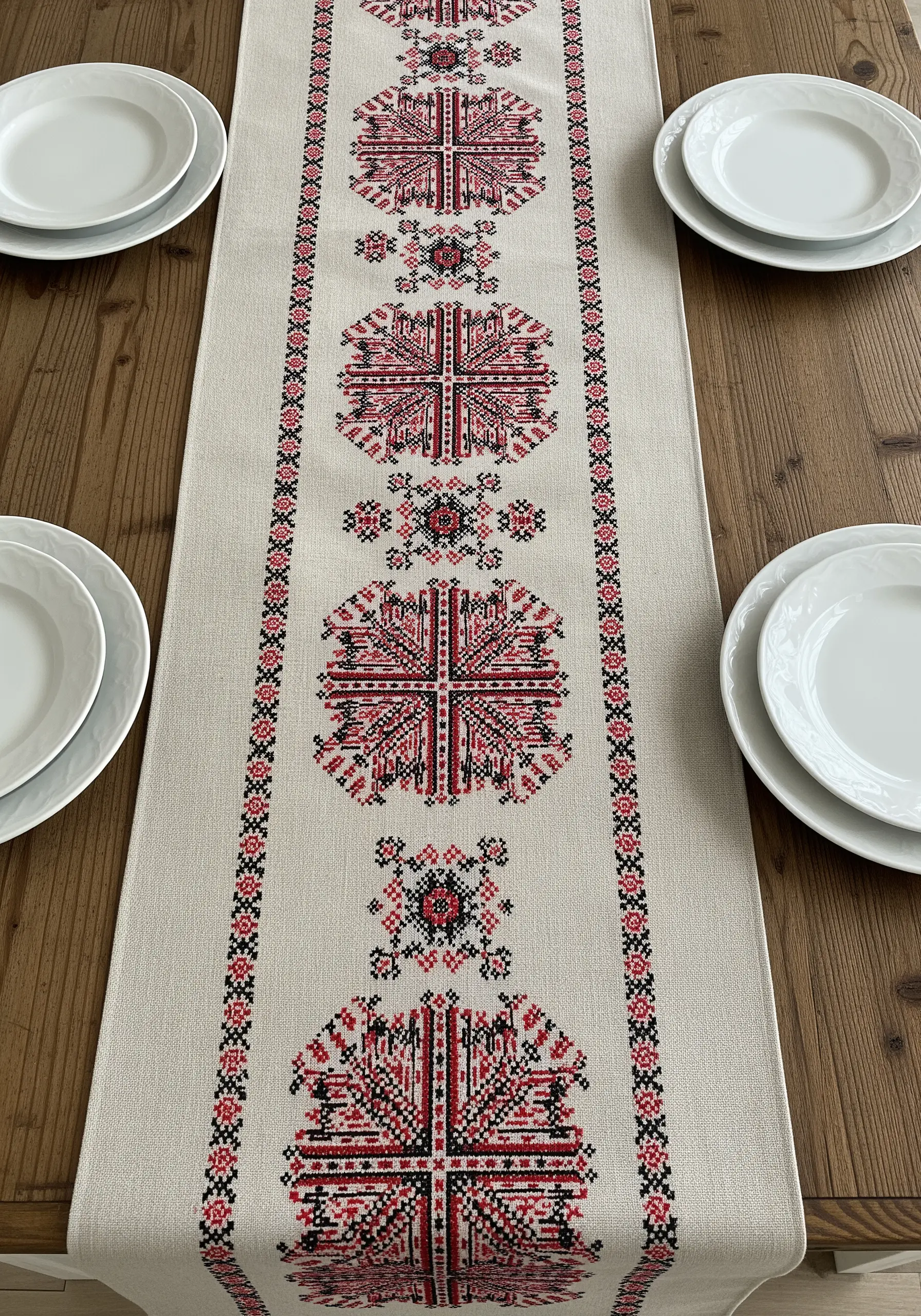 A long table runner with red and black geometric cross-stitch folk patterns.