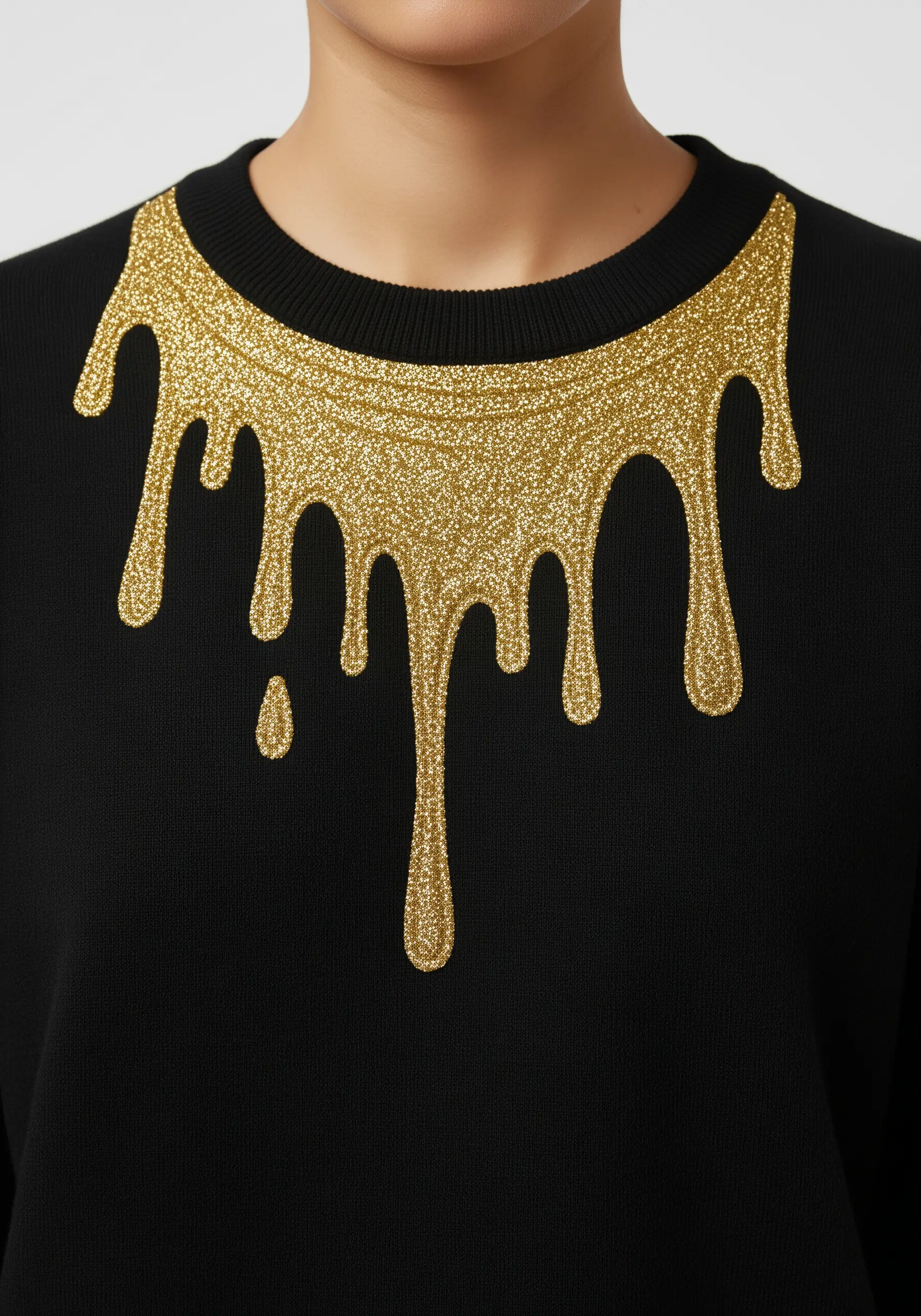 A bold, liquid gold drip pattern in glitter embroidery around the collar of a black sweater.