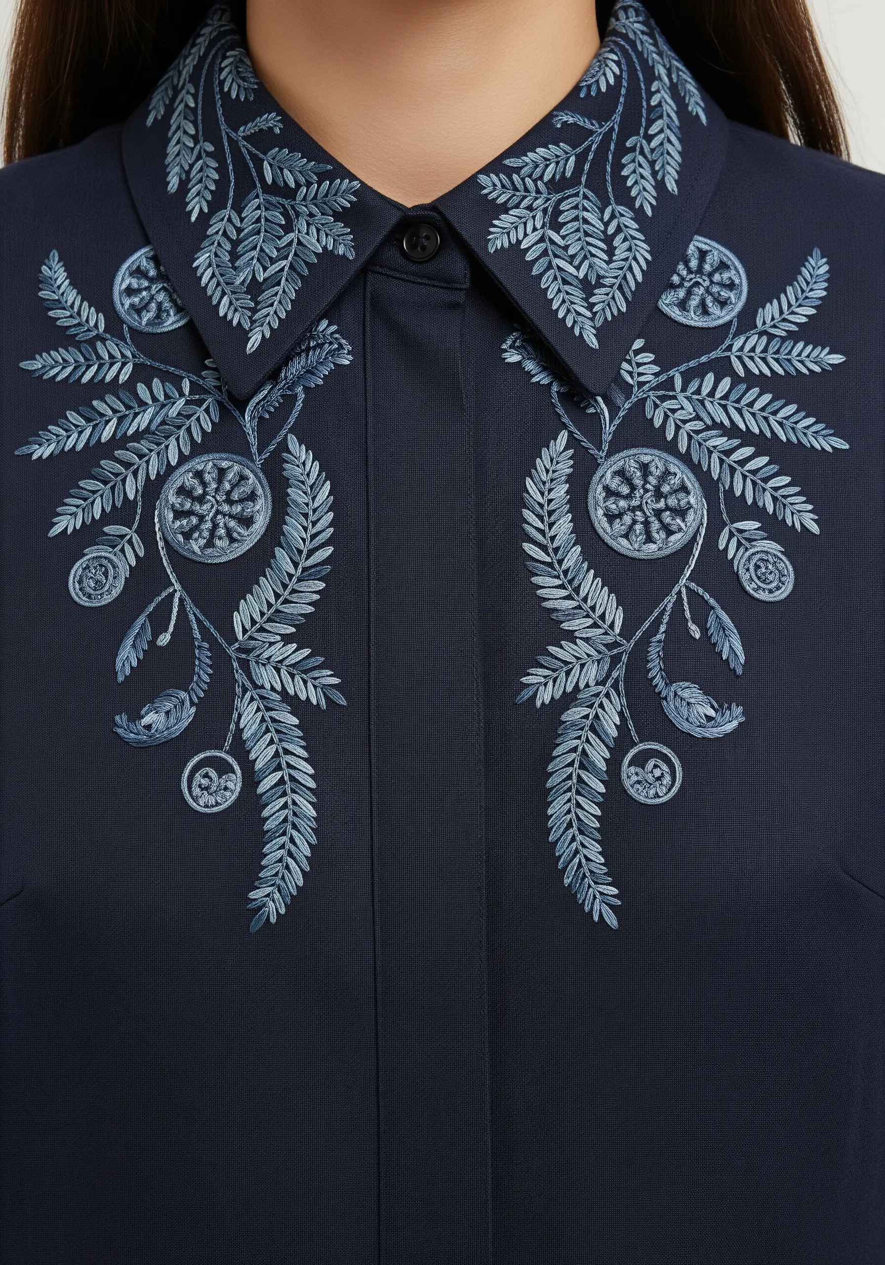 Intricate monochromatic blue foliage embroidered symmetrically on a dark navy collar.